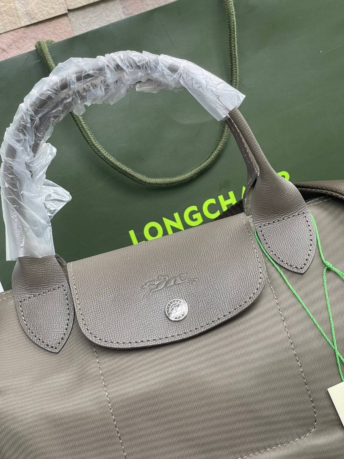 Longchamp LE PLIAGE NÉO TOP HANDLE BAG อีกหนึ่งรุ่นยอดนิยม ที่สาวๆ ต้องมีไว้เก็บไว้สักใบ กระเป๋าโท้ทใบนี้ มาพร้อมกับสีที่มีสไตล์เรียบง่าย มีสายสะพายยาวปรับสั้นยาวได้ช่วยให้คุณสามารถสะพายไหล่ได้อย่างสบาย ในตัวสายปักโลโก้อันเป็นสัญลักษณ์ ในขณะที่ที่ปิดแบบซิ
