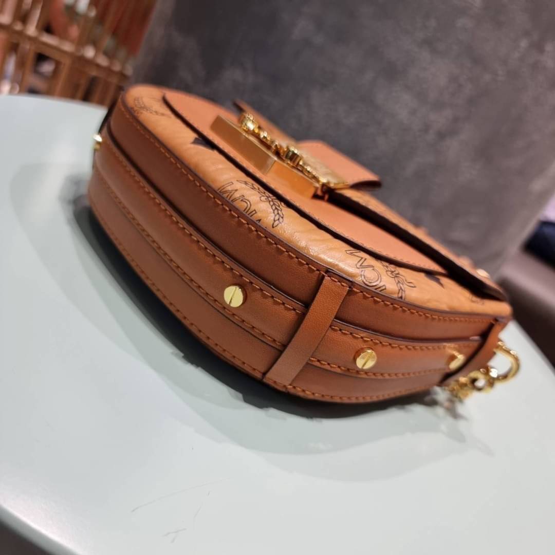 M.C.M MINI PATRICIA CROSSBODY IN VISETOS กระเป๋าสะพายไซส์มินิ แรงดีไม่มีตกน้า คอลเลคชั่นนี้ดีไซน์แปลกใหม่ ทรงโค้งมน สวยหรู ด้านข้างตกแต่งหมุดทองรอบใบ วัสดุตัวกระเป๋าเป็นหนังแคนวาสคุณภาพดี ภายในเป็นหนังกลับสีส้มโดดเด่นเป็นเอกลักษณ์ มีช่องใส่บัตรแยกให้ เปิด