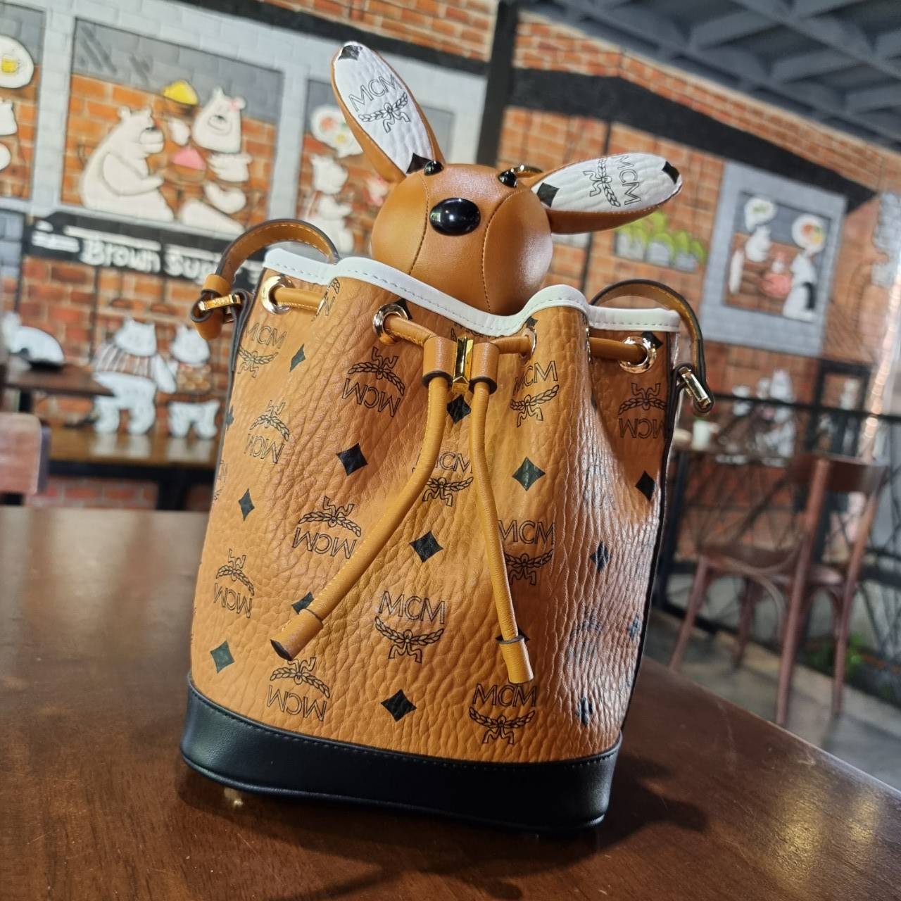 M.C.M ZOO RABBIT DRAWSTRING BAG IN VISETOS LEATHER MIX คอลเลคชั่นซูมาใหม่ ฮิตหนักมากที่เกาหลีและญี่ปุ่น ไอเท็มสุดคิ้วท์ น้องกระะต่ายโดดเด่น กระเป๋าสะพายทรง bucket ไซส์เล็กขนาดน่ารักน่าใช้ แฟชั่นสไตล์มากใบนี้ ดีไซน์น้องกระต่ายแอบในกระเป๋า และสามารถนำออกมาห