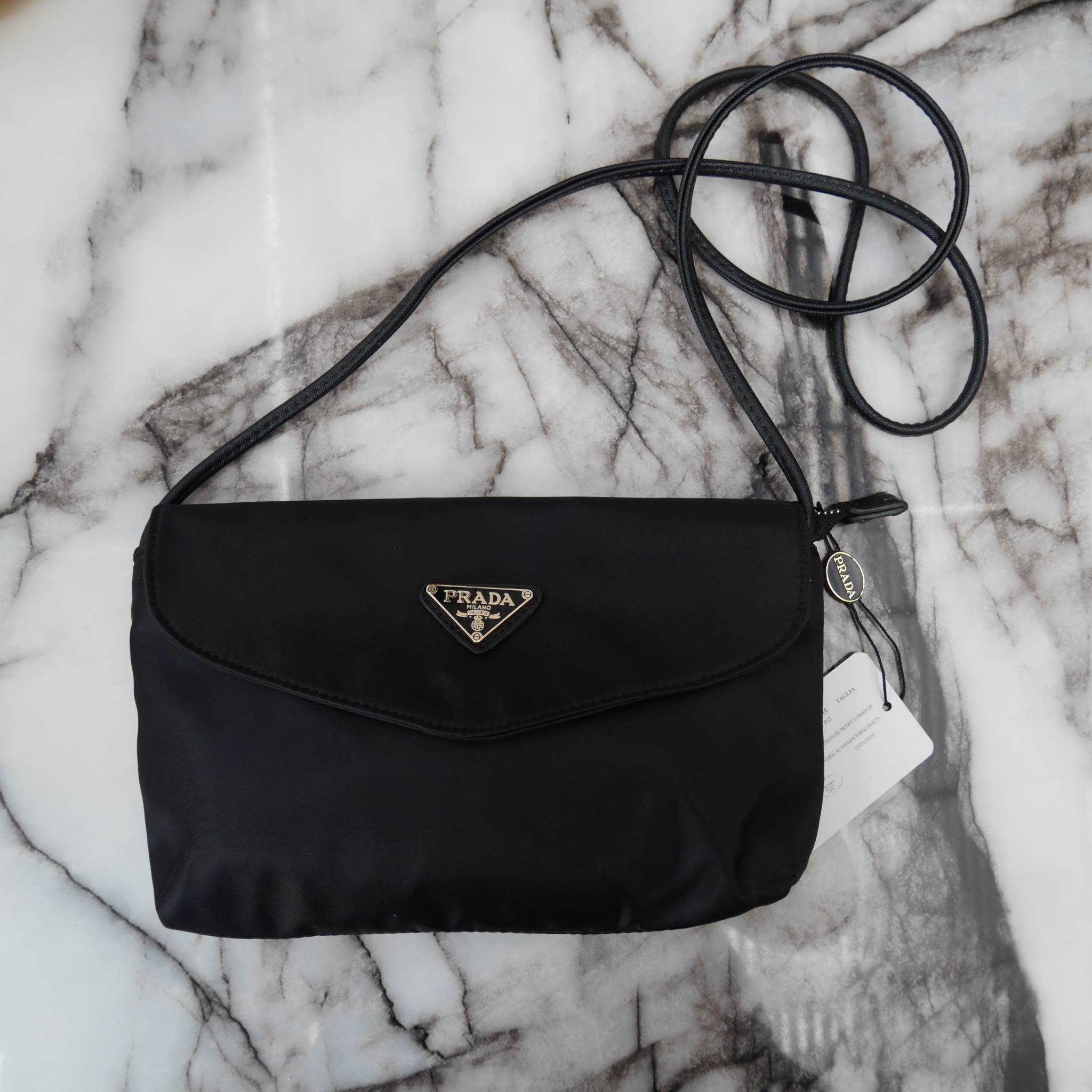 Best Seller! จากงานพรีเมี่ยมกิ้ฟ จากเคาเตอร์ต่างประเทศ จากแบรนด์ PRADA ค่า เป็น กระเป๋าผ้าไนล่อน ตามแบบฉบับของแบรนด์เลย ใบนี้มีสายยาวให้คะ เลิศมาก สะพายเป็น shoulder bag ได้เลย ขนาดกำลังดีคะ ตัวกระเป๋าเบามาก ใส่มือถือได้ทุกรุ่น ใช้แล้วสวยมากๆ อะไหล่ทองหรู