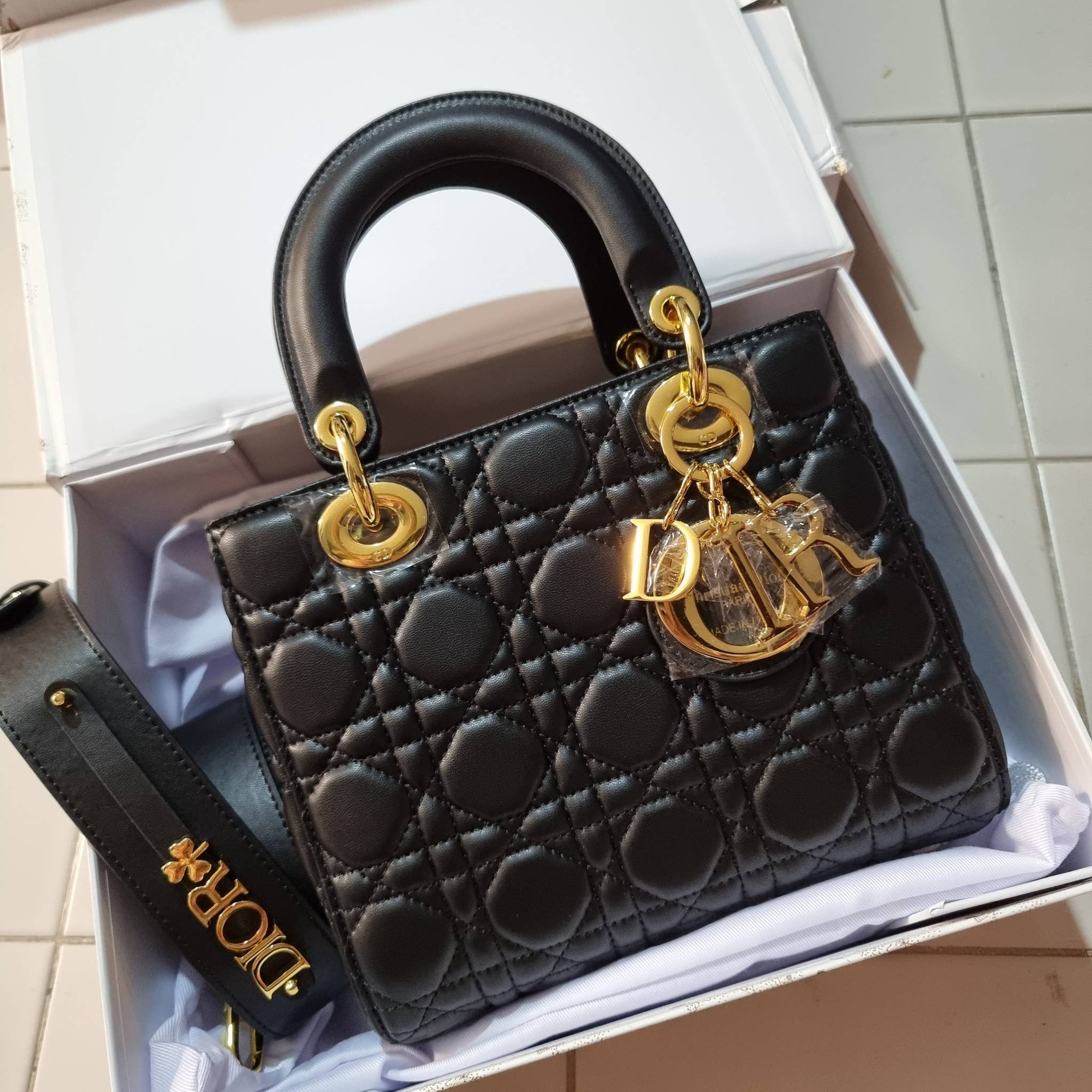 DIOR CD LADY BAG กระเป๋าสะพายข้างพรีเมี่ยมกิ๊ฟสุดฮอต ดีไซน์เรียบง่าย แต่แฝงไปด้วยความหรูหรา ทรงกล่องคลาสสิค โดดเด่นด้วยพวงกุญแจอะไหล่สีทอง วัสดุหนังแท้ มีหูจับในตัวและสายครอสบอดี้สุดเลิศ ที่มาพร้อมอะไหล่ฟอนท์สีทองเรียงร้อยในสายหนัง แต่งเติมดีเทลอัพราคาไปอ