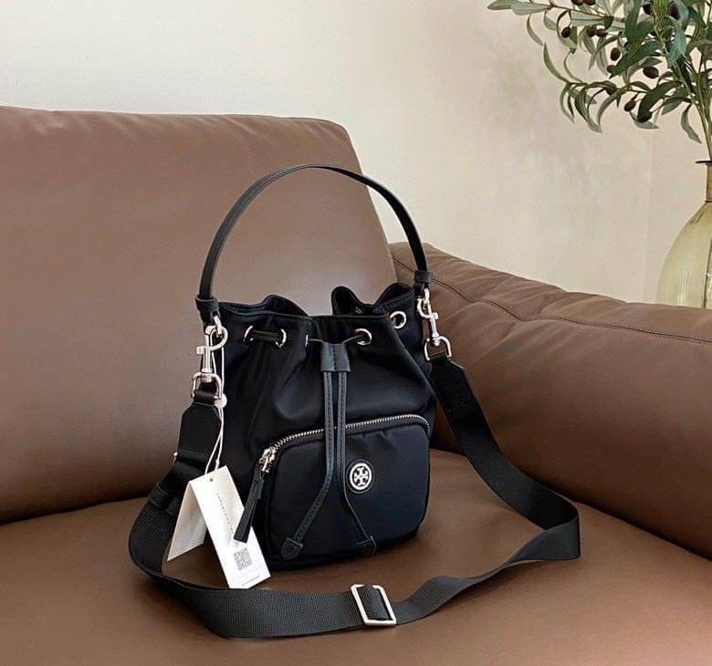 Tory Burch Virginia Nylon Bucket Bag / Tory Burch logo-plaque bucket bag กระเป๋าสะพายทรงบัคเก็ต เปิด-ปิดหนังรูดปากกระเป๋า มีหูหิ้วในตัว คล้องแขนเก๋ๆ ภายในเป็นช่องโล่ง มีช่องย่อย ใส่ของสำคัญจุกจิกได้ มีสายครอส จะสะพายไปไหนก็ได้ทุกโอกาส สวยเลิศทุกสี พร้อมส่