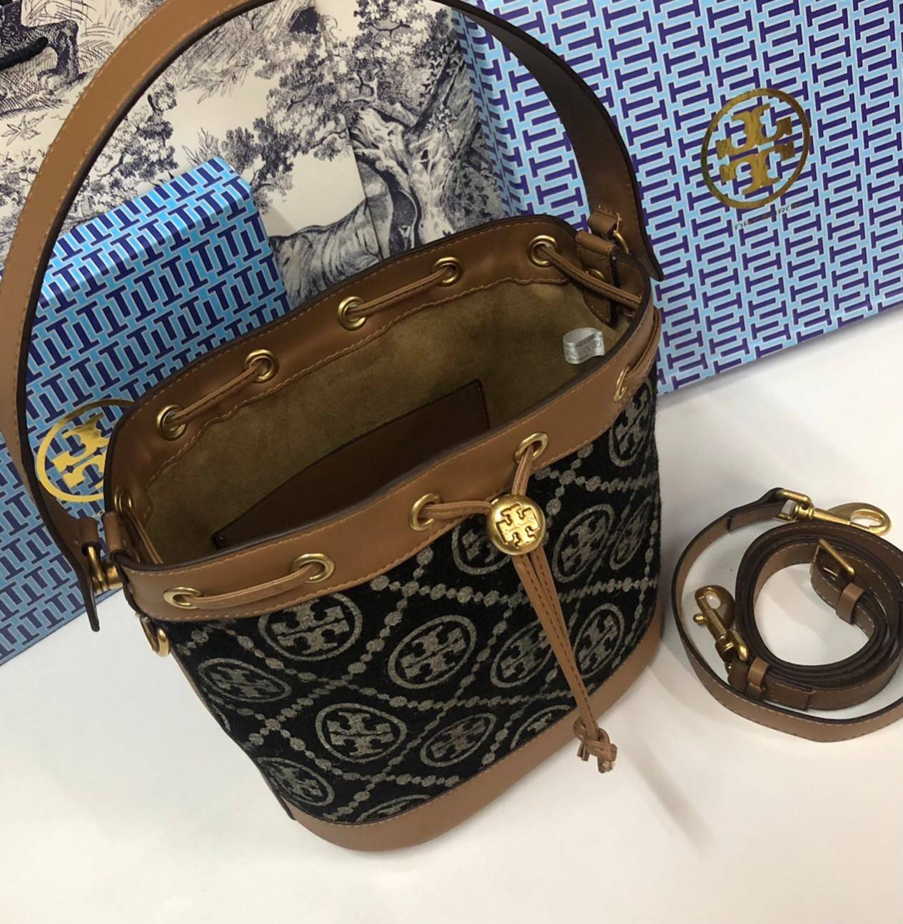 Medium : Tory Burch T Monogram Chenille Bucket Bag เปิดตัวอีกหนึ่งรุ่นกับกระเป๋าลาย T MONOGRAM รุ่นใหม่ล่าสุดจาก TORY BURCH พลาดไม่ได้กับโลโก้สุดคลาสสิก ลวดลาย T Monogram คือวัสดุ chenille หรือที่เรียกว่า ด้านไหมกำมะหยี่ มารังสรรค์ลงบนกระเป๋าBucketใบนี้ เ