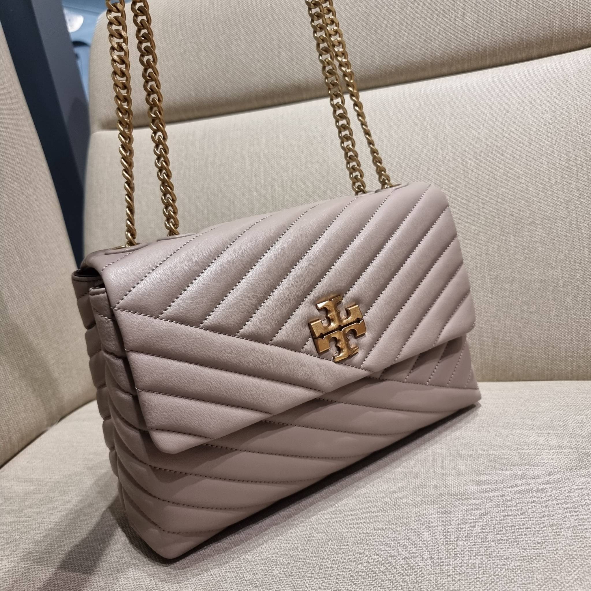 TORY BURCH KIRA CHEVRON CONVERTIBLE SHOULDER BAG กระเป๋าสะพายรุ่นยอดฮิต ไซส์ใหญ่จัดเต็มให้เน้นๆ ใช้ยังไงก็ดูหรู ดีไซน์เฉพาะตัว วัสดุหนังแกะ สัมผัสนิ่ม เปิด-ปิดด้วยกระดุมแม่เหล็ก ภายในเป็นช่องโล่ง แบ่งสัดส่วนไว้ดีมากๆ ใส่กระเป๋าสตางค์ มือถือ เครื่องสำอางค์