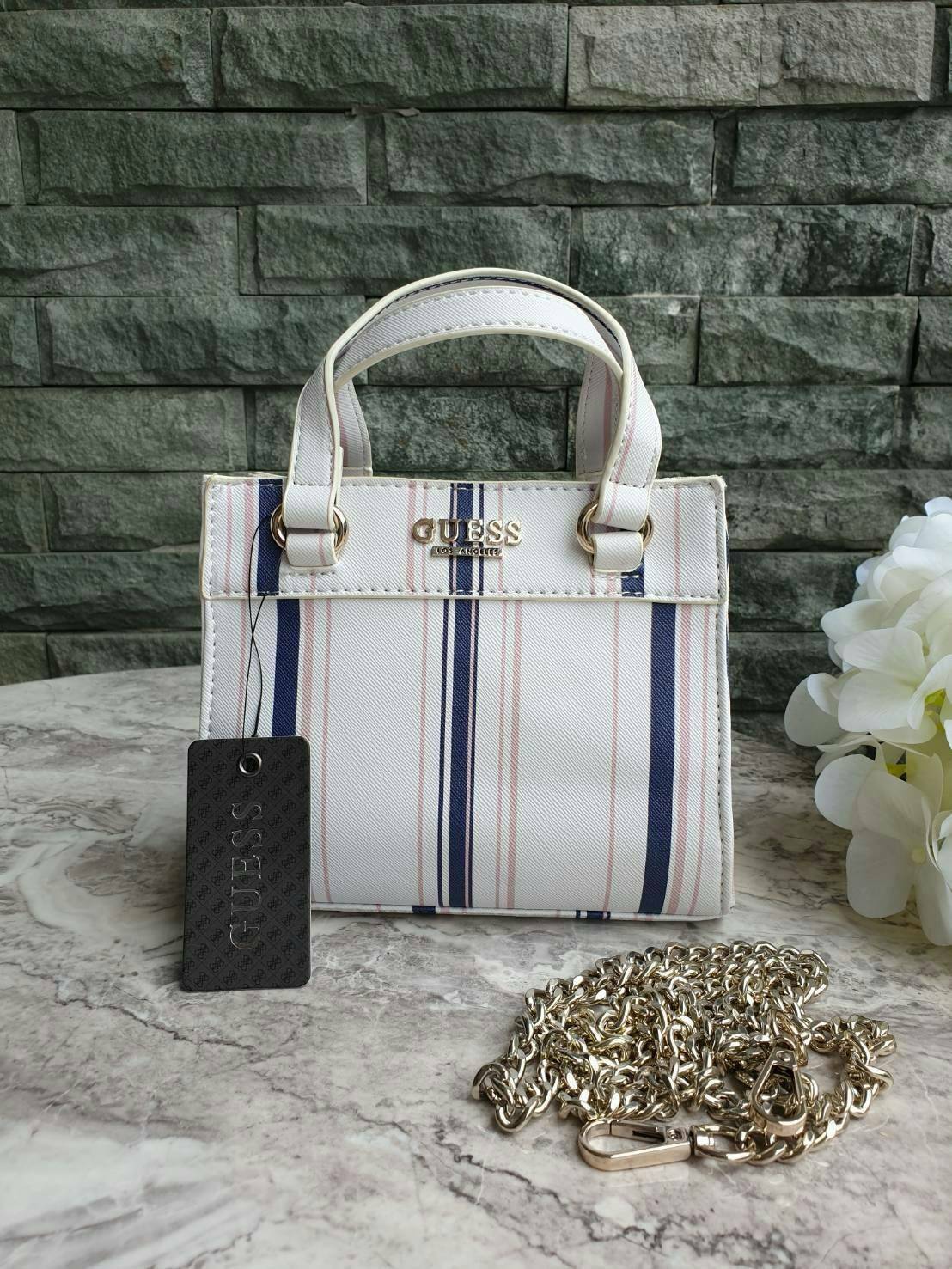 GUESS TAYLOR MINI SATCHEL CROSSBODY BAG กระเป๋าสะพายใบเล็ก สไตล์ สวยหรู คุณหนู ไฮโซ น่ารักมากๆ วัสดุหนังpu เย็บลายตาราง หนังนิ่ม จับนุ่มมือ และ ลายทาง หนัง saffiano ตั้งอยู่ทรง แบบน่ารักไม่ซ้ำใคร ด้านหน้าประดับโลโก้แบรนด์ อะไหล่ทอง มาพร้อมสายโซ่ ถอดออกได้