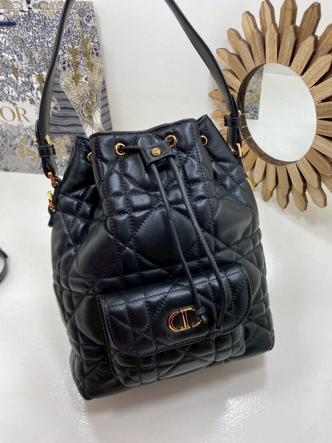 ORI หนังแท้ | Small Dior Caro bucket bag กระเป๋าทรงบักเก็ต รุ่นใหม่ประจำ Fall 2025 โดดเด่นด้วยดีไซน์ที่ทันสมัยและสง่างาม ได้รับการรังสรรค์ขึ้นจากหนังแกะสีดำเดินด้ายลาย Macrocannage พร้อมกับช่องเก็บของขนาดใหญ่แบบเชือกรูดปิด