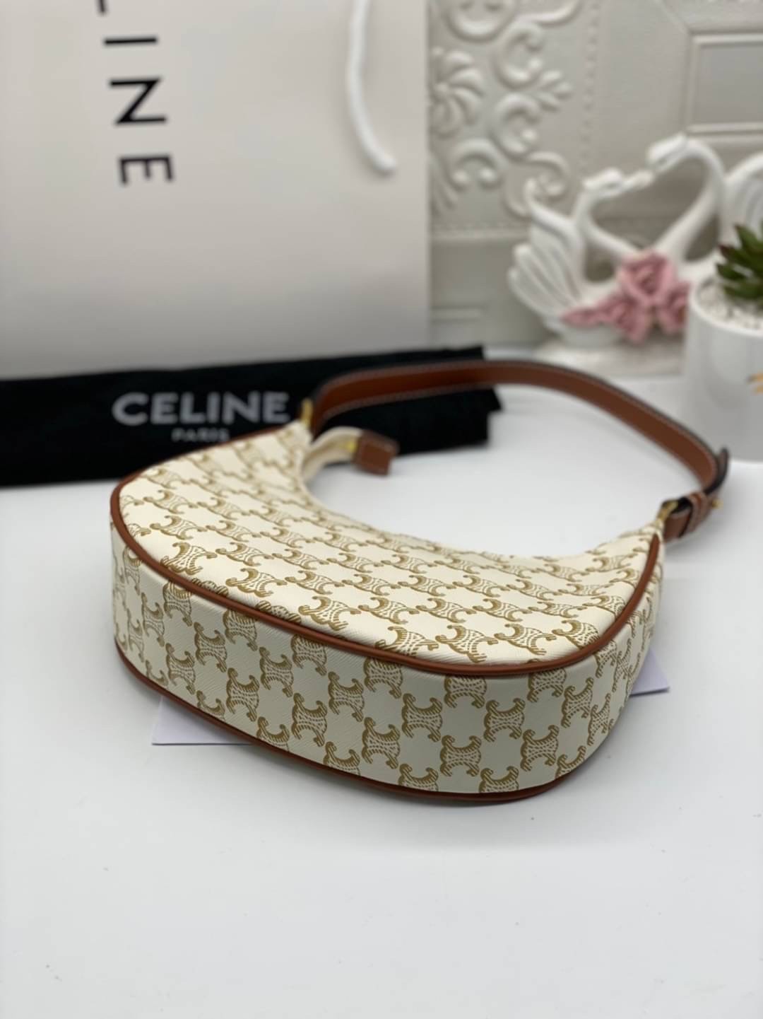 หนังแท้ CELINE AVA / CELINE Vintage Classic Ava bag 1 ใน คอลเลคชั่น “Triomphe Canvas” มาพร้อมสายสะพายไหล่ที่ปรับความยาวได้ และเนื่องจากช่วงล่างของกระเป๋ามีขนาดใหญ่กว่าช่วงบน จึงทำให้ไม่เสียทรงเมื่อเราใส่สิ่งของอย่างกระเป๋าสตางค์หรือโทรศัพท์มือถือ หากดูภาพ