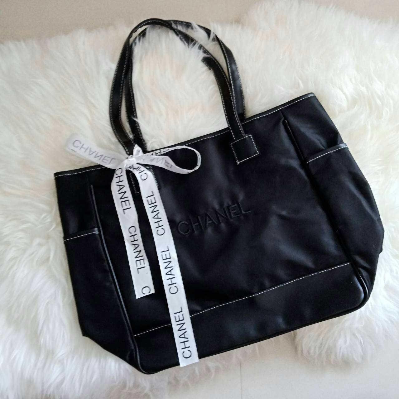 NEW! Chanel Shopping Bag with Ribbin พรีเมี่ยมกิ้ฟของแท้จาก Chanel Cosmetic Counter วัสดุ Polyester & Nylon เนื้อหนาตัดหนังเรียบสีดำเพิ่มความแข็งแรงอยู่ทรง เปิดปิดด้วยซิปสะดวกใช้ น้ำหนักเบา จุสุดๆค่ะ ภายในมีช่องซิปและช่องใส่ของหลายช่อง ใส่เอกสาร A4 หนังสื