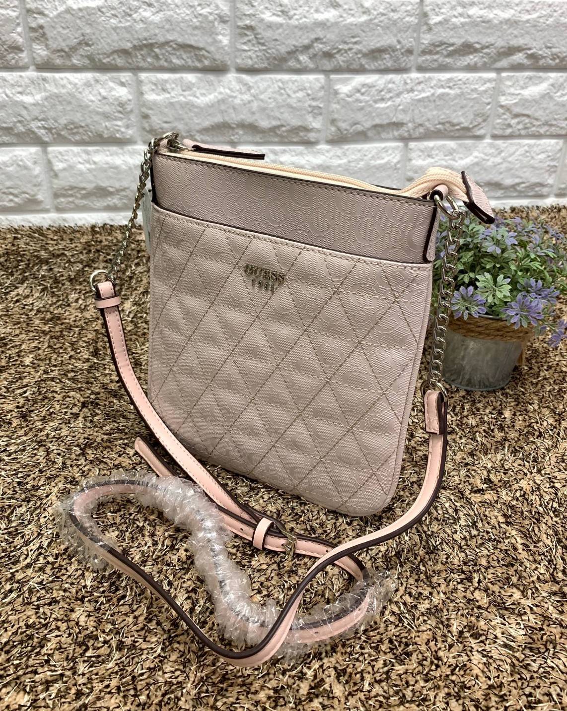 GUESS MINI CROSSBODY BAG กระเป๋าสะพายข้างหรือ crossbody วัสดุหนังแก้วลายทั้งใบ ด้านหน้ามีโลโก้แบรนด์ และช่องโล่งหนึ่งช่อง เปิดปิดกระเป๋าแบบซิป ภายในโล่ง ใส่มือถือ, กระเป๋าสตางค์ใบสั้น, สมุดแบงค์ จุพอประมาน มีช่องเล็กใส่ของจุกจิกอีกช่อง สายสะพายแบบโซ่ต่อหน