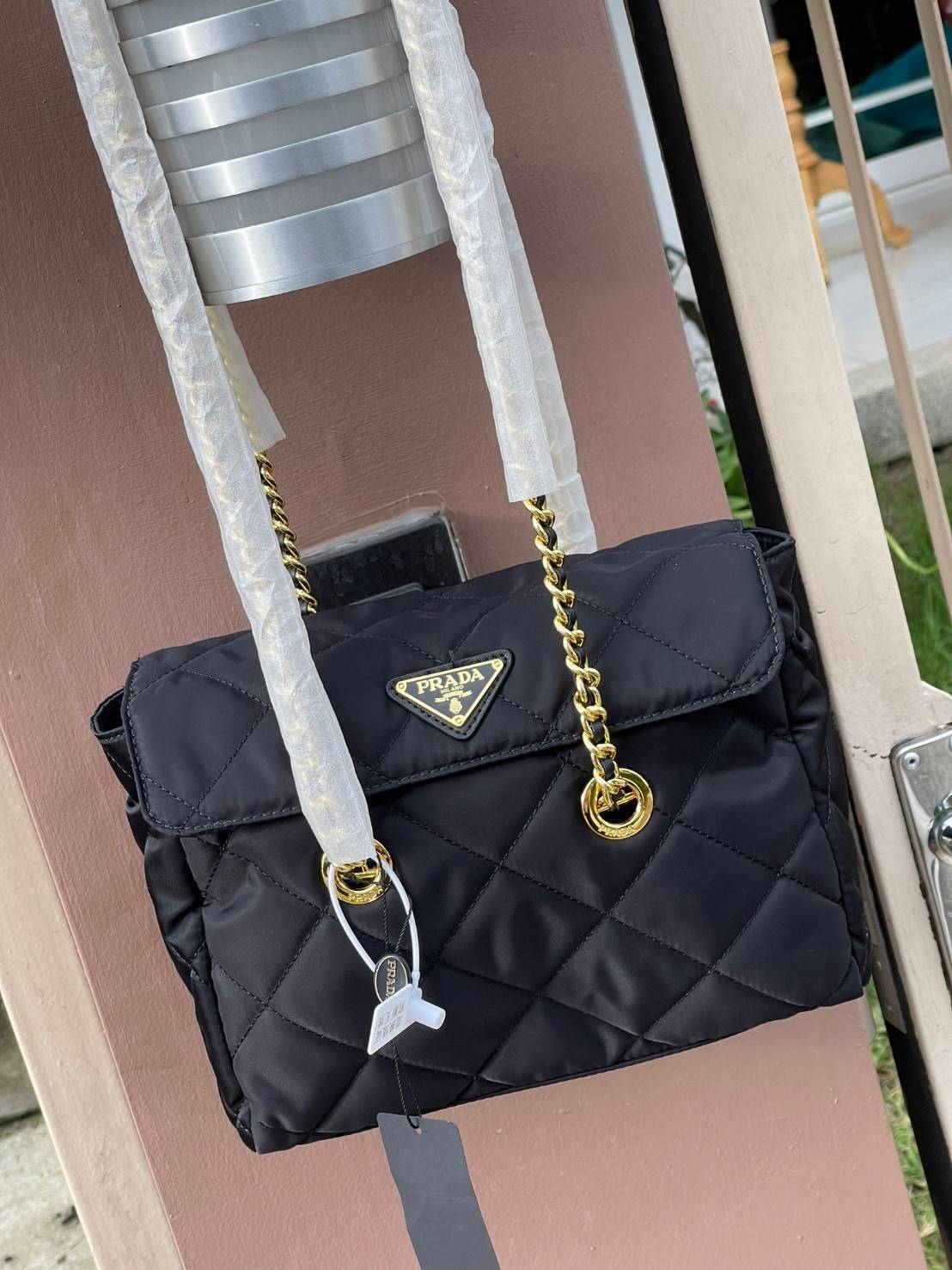 Prada Black Quilted Nylon Vintage Shoulder Bag ถือว่าเป็นแบรนด์ที่ได้รับการขนานนามว่าเป็น "แบรนด์คลาสสิกที่แปลกใหม่ ดูเก่าแต่ทันสมัย" กระเป๋าสะพายไหล่ใบนี้ วัสดุเป็นไนลอนที่ถือเป็น Iconic ของแบรนด์ มาพร้อมกับดีเทลที่ใช้สายสะพายโซ่ร้อยเข้ากับหนัง