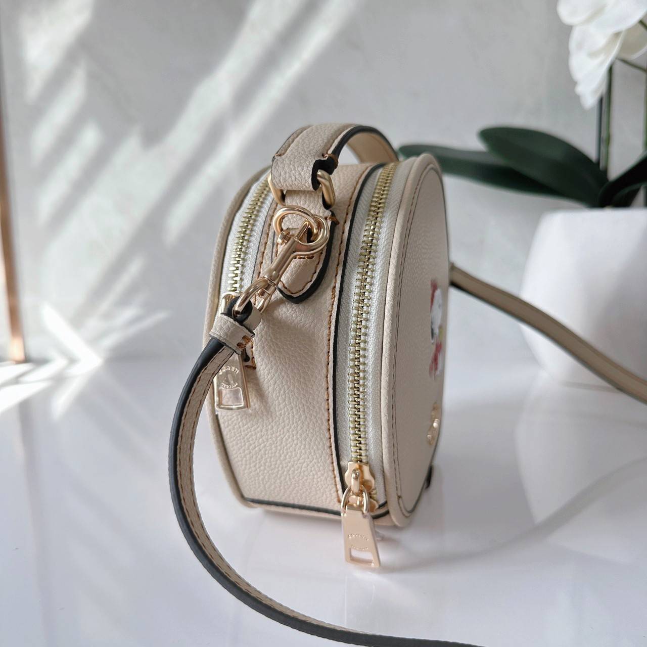 COACH X PEANUTS CANTEEN CROSSBODY WITH SNOOPY PRESENT MOTIF (CE845,CF290) กระเป๋าสะพายข้างทรงกลมไซส์มินิ มีหูจับ วัสหนังแท้ ด้านหน้าโดดเด่นด้วยรูปการ์ตูนSnoopy