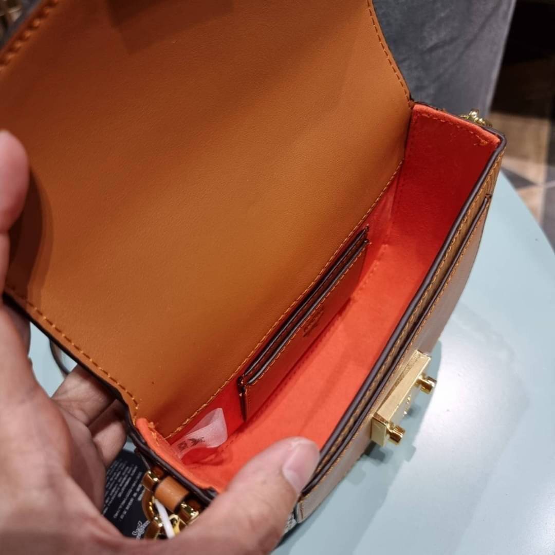 M.C.M MINI PATRICIA CROSSBODY IN VISETOS กระเป๋าสะพายไซส์มินิ แรงดีไม่มีตกน้า คอลเลคชั่นนี้ดีไซน์แปลกใหม่ ทรงโค้งมน สวยหรู ด้านข้างตกแต่งหมุดทองรอบใบ วัสดุตัวกระเป๋าเป็นหนังแคนวาสคุณภาพดี ภายในเป็นหนังกลับสีส้มโดดเด่นเป็นเอกลักษณ์ มีช่องใส่บัตรแยกให้ เปิด