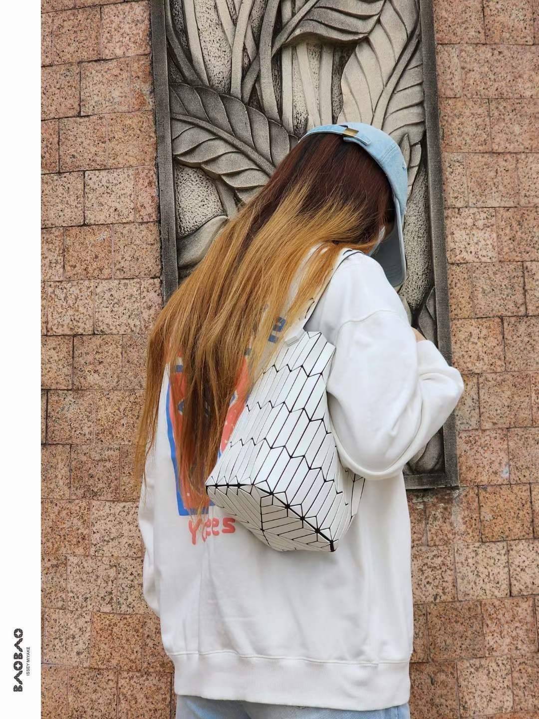 Large : Baobao Issey Miyake Large Bucket กระเป๋าบัคเก็ตขนาดใหญ่สามารถใช้ใส่ร่มพับได้หรือขวดน้ำขนาดเล็กได้ ซีรีย์ใหม่นี้มีจุดเด่นที่แผ่นรูปทรงสี่เหลี่ยมด้านขนานในแนวตั้ง เกิดเป็นรูปทรงสามมิติซึ่งแตกต่างไปจากรูปทรงที่เกิดขึ้นจากแผ่นสามเหลี่ยม หูหิ้วสามารถขย