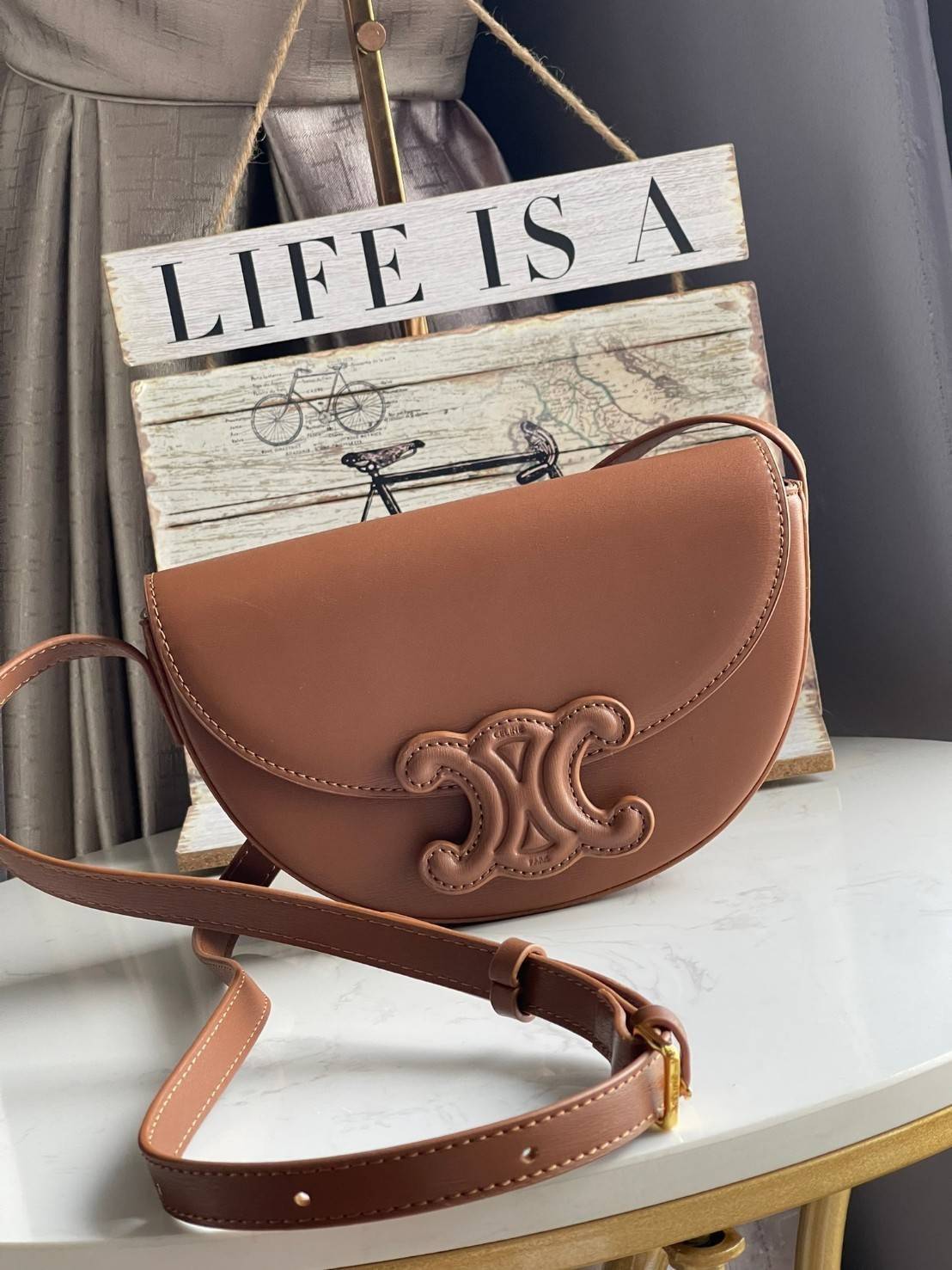 CELINE BESACE CUIR TRIOMPHE IN SMOOTH กระเป๋ารุ่นนี้นำเสนอในรูปทรงฮาล์ฟมูนที่ตอนนี้กำลังงมาแรง เปิดด้วยกระดุมแป๊กเพื่อเผยให้เห็นช่องภายในที่กว้างขวางและกระเป๋าด้านในแบบแบน คุณสมบัติที่โดดเด่นอีกอย่างของกระเป๋าอยู่ที่โลโก้ขนาดใหญ่ รูปทรงสะดุดตา สามารถสะพาย