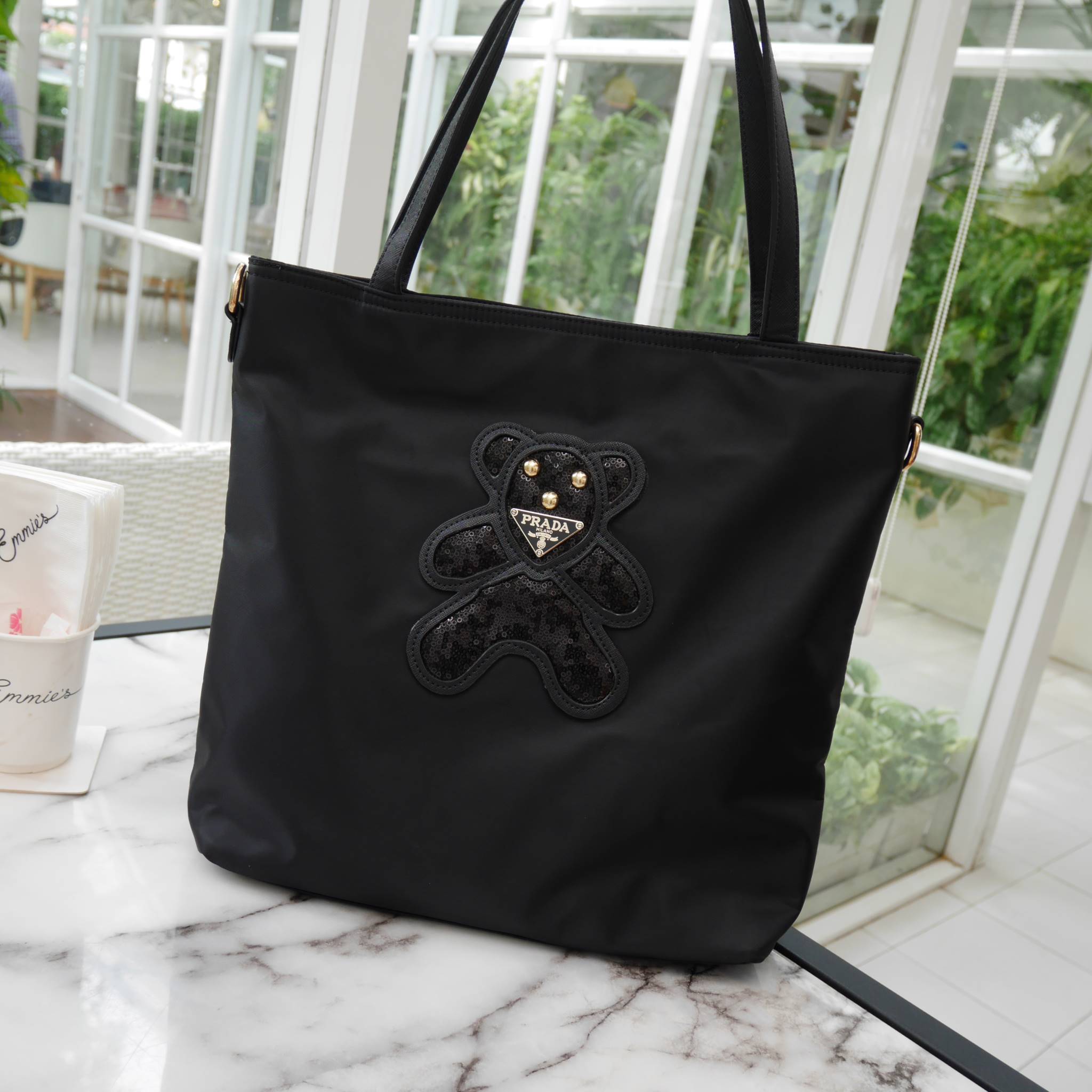 งานขายดีคะ ♡♡ กระเป๋าสะพาย ทรง TOTE จากแบรนด์ PRADA มาค่า ตัวกระเป๋าเป็น nylon ทั้งใบ สะพายเป็น shoulder bag หรือถือได้ค่ะ ด้านหน้าเป็นลายหมี ปักกลิ้ตเตอร์ + logo brand ใช้แล้วสวยมากๆ อะไหล่ทองหรูมาก จุของคุ้ม ใส่หนังสือ หรือ MacBook ได้ค้า 