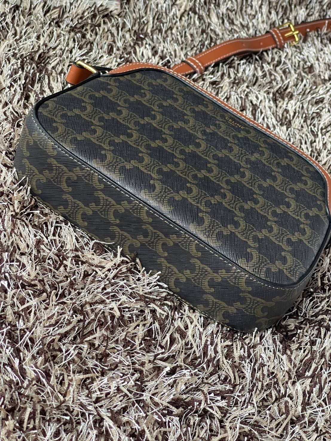 CELINE Triomphe Canvas Small Camera กระเป๋าสะพายไหล่สุดเก๋ใบนี้ผลิตจากผ้าใบเคลือบอย่างดีพร้อมขอบหนังสีน้ำตาล มาพร้อมสายสะพายหนังปรับระดับได้พร้อมฮาร์ดแวร์สีทองและซิปด้านบน ภายในบุด้วยผ้าสีน้ำตาล ลวดลาย triomphe อันเป็นเอกลักษณ์ของแบรนด์ และเป็นกระเป๋าสะพา