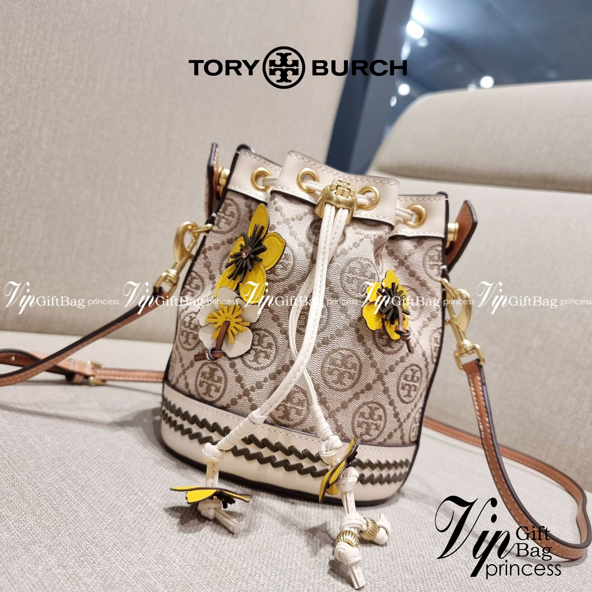 TORY BURCH MINI T MONOGRAM FLORAL BUCKET BAG คอลเลคชั่นใหม่ พร้อมเสิร์ฟความสวยให้ถึงบ้าน!! กระเป๋าบัคเก็ตทรงยอดนิยม ไซส์มินิ ดีไซน์ใหม่ล่าสุด สไตล์งานคราฟ มีลูกเล่นประดับดอกไม้กับตัวกระเป๋า และตัวรูดสาย วัสดุผ้า jacquard ตัดสลับหนังแท้ หูจับและขอบกระเป๋าต
