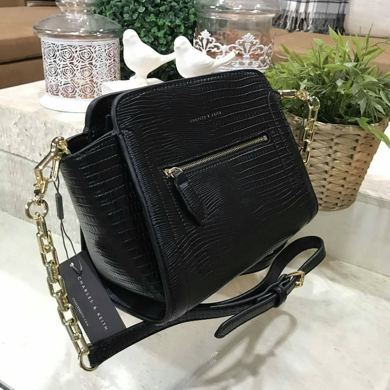 CHARLES & KEITH TRAPEZE CROSSBODY BAG กระเป๋าถือหรือสะพายดีไซน์ยอดนิยมหนังอยู่ทรงสวย ด้านหน้าสกรีนโลโก้ และมี 1 ช่องซิป เปิดปิดด้วยซิป ภายในมีช่องใส่ของ และช่องซิปเล็ก ใส่กระเป๋าสตางค์ใบยาว มือถือ ของใช้ได้เยอะ พร้อมสายสะพายยาวโซ่ต่อหนังปรับได้ถอดได้ มีหม