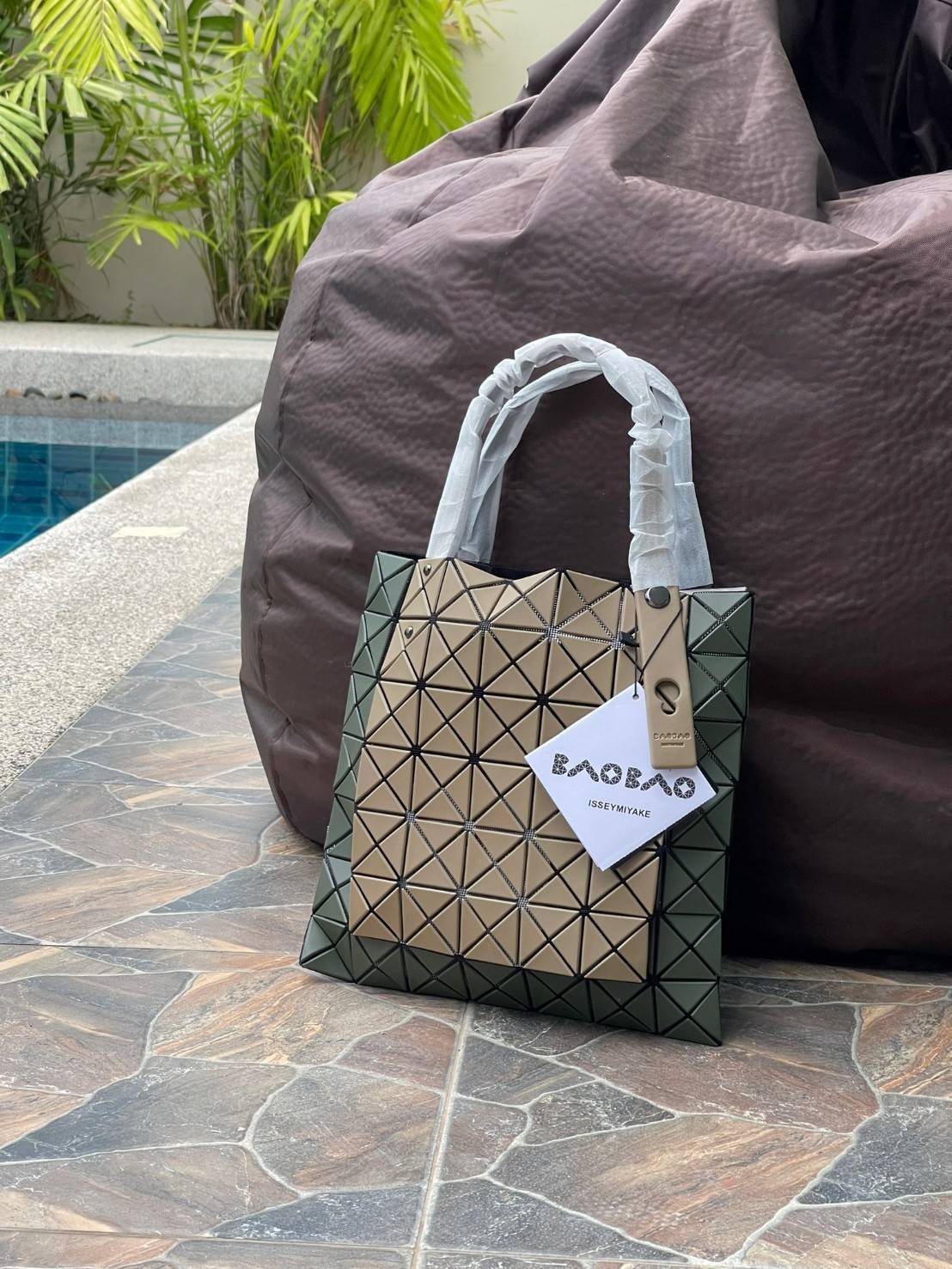 Baobao Issey Miyake Prism Kangaroo tote bag กระเป๋าถือทรงโท้ทที่ประดิษฐ์ขึ้นอย่างเชี่ยวชาญในญี่ปุ่น มาพร้อมแผงเรขาคณิตสำหรับการออกแบบที่ได้รับแรงบันดาลใจจากกระดาษพับ ซิลลูเอทอันเป็นเอกลักษณ์นี้ปิดท้ายด้วยสายรัดแบบอสมมาตร มีการพัฒนาโครงสร้างทรงสามเหลี่ยมเพ