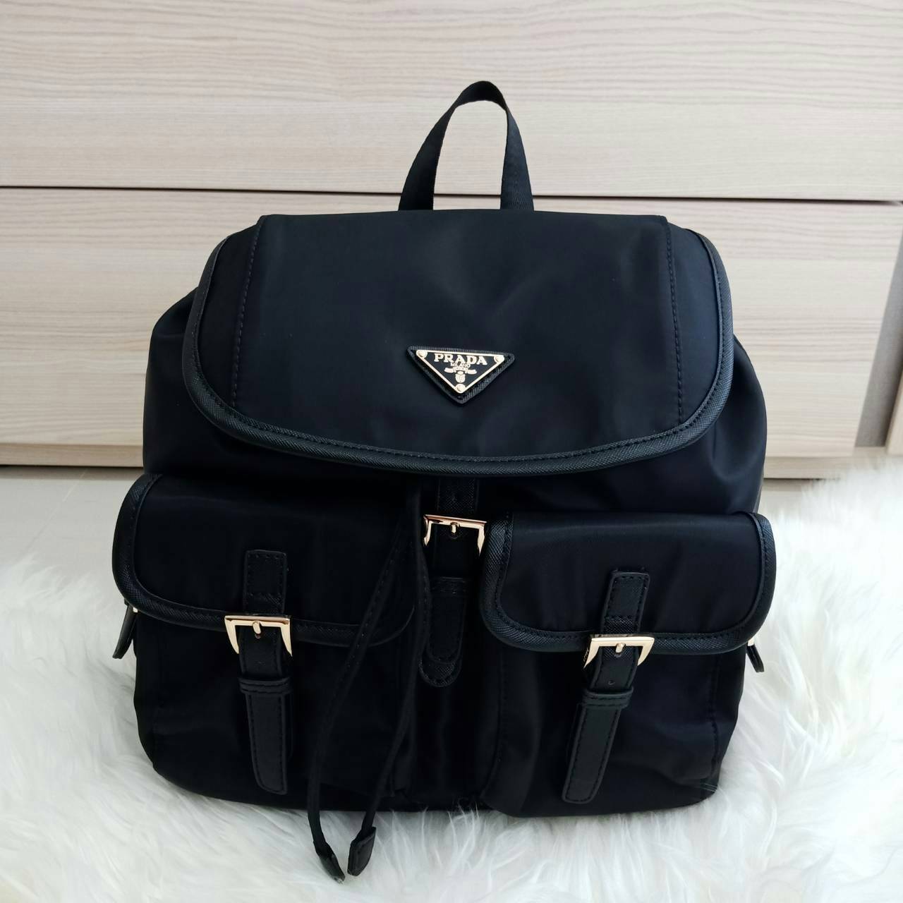 Prada nylon backpack with pocket กระเป๋าเป้ทรง signature จาก วัสดุ nylon เนื้อหนา ด้านหน้าประดับ logo brand, มีช่องใส่ของ 2 ช่อง กระเป๋าเปิดปิดด้วยกระดุมแม่เหล็ก และ drawstring ด้านในมีป้ายหนัง logo brand บุผ้าลายแบรนดอย่างดี สายสะพายปรับได้ freesize สายก