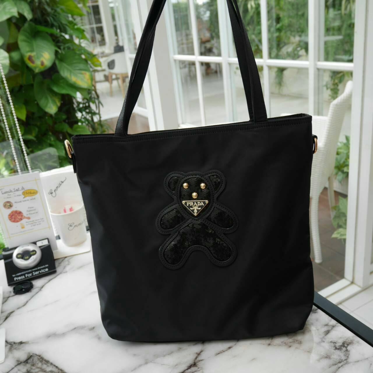 ReStock! งานขายดี ได้ กระเป๋าสะพายไหล่ ทรง TOTE จากแบรนด์ PRADA มาค่า เป็น กระเป๋าผ้าไนล่อน ตามแบบฉบับของแบรนด์เลย ใบนี้มีสายยาวให้ค่ะ สะพายเป็น shoulder bag หรือ ถือได้ค่ะ ด้านหน้าเป็นลายหมี ปักกลิ้ตเตอร์ +logo brand ใช้แล้วสวยมากๆ อะไหล่ทองหรูมาก จุของค