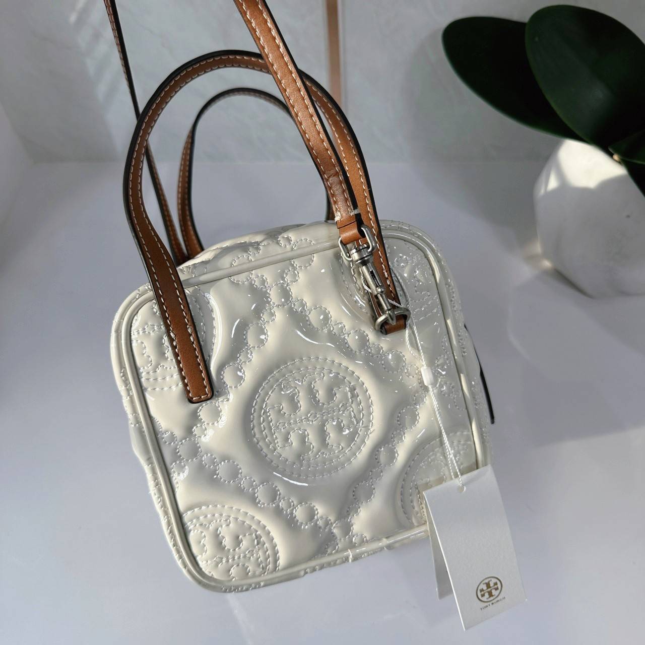Tory Burch T Monogram Embroidered Patent Cube คอลเลคชั่นใหม่ รุ่นลิมิเต็ดรูปทรงใหม่ T Monogram สุดcube วัสดุหนังแท้ เปิด-ปิดด้วยซิป ภายในกว้าง มีช่องแยก 1 ช่อง สามารถใส่โทรศัพท์มือถือได้ทุกรุ่น สามารถถือหิ้วหรือสะพายได้ สายสามารถถอดและปรับระดับได้คะ