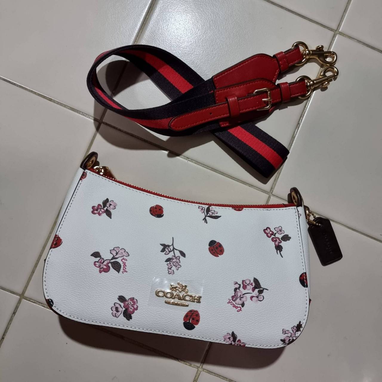 COACH C7973 JES BAGUETTE WITH LADYBUG FLORAL PRINT คอลเลคชั่นใหม่ล่าสุด พร้อมเสิร์ฟความสวยถึงบ้านเช่นเคย!! กระเป๋าสะพายทรงบาแกตต์ ดีไซน์ย้อนยุค ที่แอบแฝงความเรียบหรูดูแพงอยู่ในตัว โดดเด่นด้วยสายสะพายเส้นใหญ่ โทนสีคอนทราส ทำให้ไอเท็มนี้ดูมีลูกเล่นมากขึ้น ว