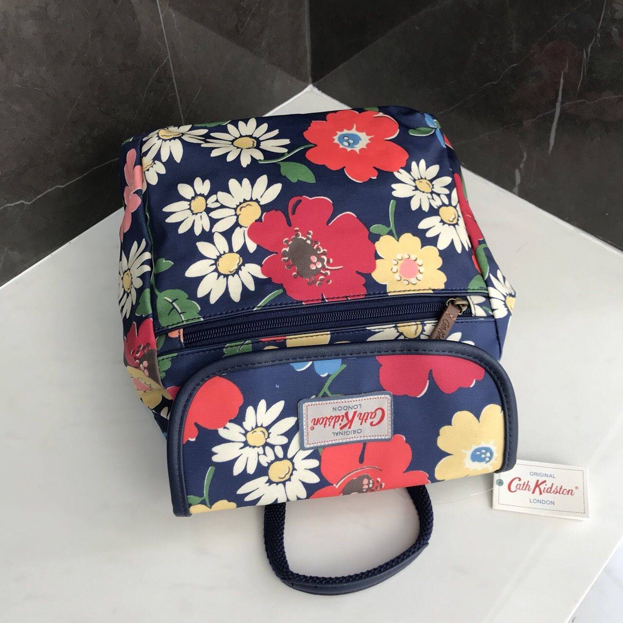 Cath Kidston Backpack Bag กระเป๋าถือหรือเป้สะพายหลัง วัสดุCanvas+Polyester อย่างดี เนื้อหนา น้ำหนักเบา ประดับโลโก้ด้านหน้า เปิดปิด ด้วยกระดุมเเม่เหล็กทั้งด้านนอก/ใน มีช่องซิปด้านหน้าใส่ กระเป๋าสตางค์ หรือมือถือได้ หัวซิปหนังปั๊มโลโก้ ภายในมี ช่องเล็ก 1 ช่