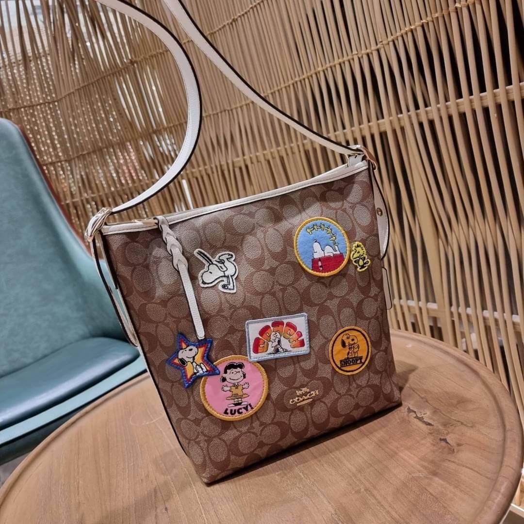 OUTLET 】COACH C4112 COACHxPEANUTS VAL DUFFLE IN SIGNATURE CANVAS WITH VARSITY PATCHES ใหม่ล่าสุด กระเป๋าทรงดัฟเฟิล ที่มาพร้อมเหล่าผองเพื่อนสนูปพี สวยมีเอกลักษณ์ ทรงกระเป๋าไม่ซ้ำใคร แถมยังใส่ของได้จุใจไปอีก วัสดุหนังแคนวาสคุณภาพดี ด้านหลังมีช่องซิป กระเป๋า