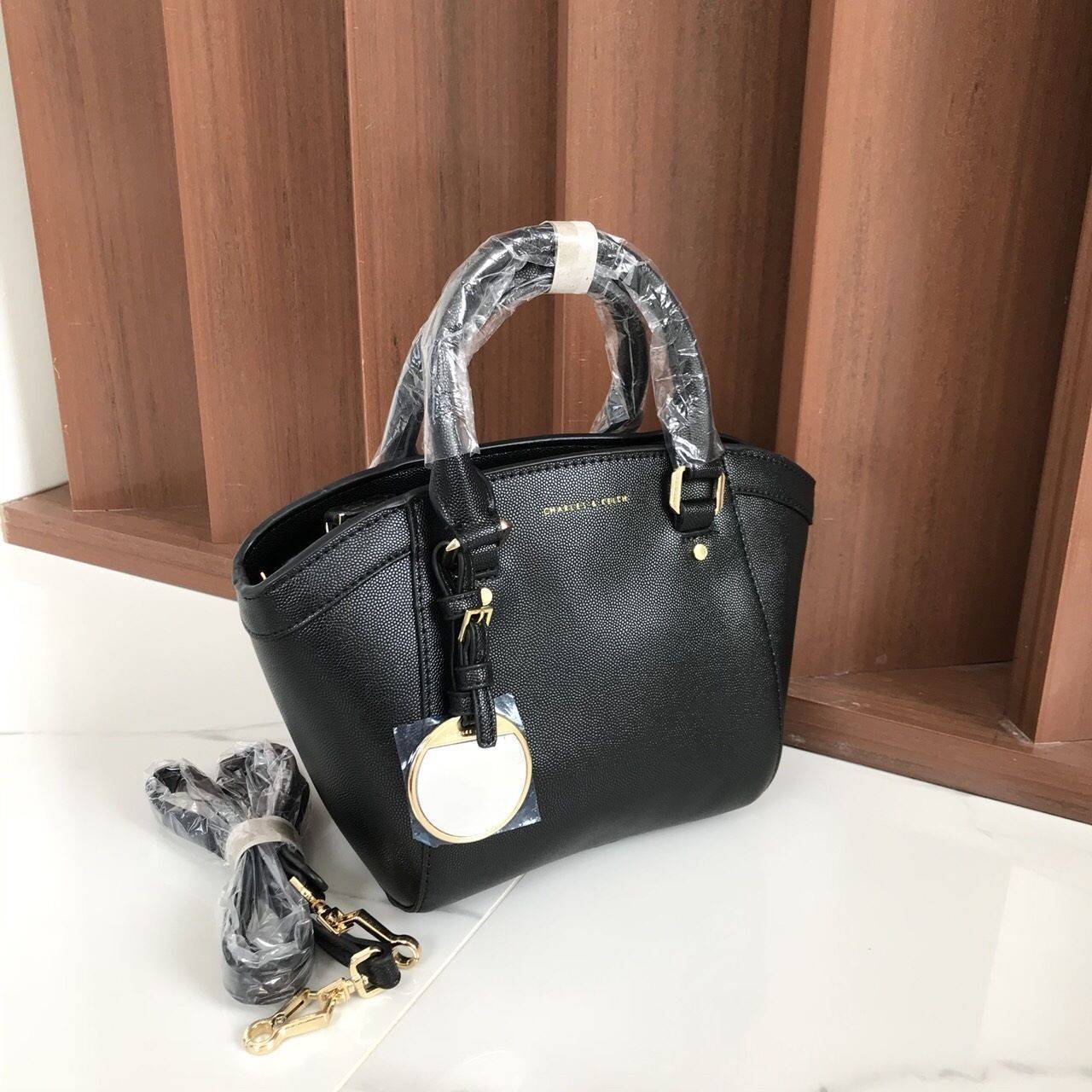 CHARLES & KEITH CITY BAG กระเป๋าถือหรือสะพาย ตั้งอยู่ทรงสวย มีโลหะรองฐาน เปิดปิดด้วยซิปเดียว ภายในมี 2 ช่องเล็กด้านหน้าประดับด้วยกระจกทรงกลม ใช้งานได้จริง ปั้มโลโก้แบรนด์ มาพร้อมสายสะพายยาว ปรับระดับและถอดสายได้ หูพับลงได้ น้ำหนักเบา ต้องมีไว้ครอบครองสักใ