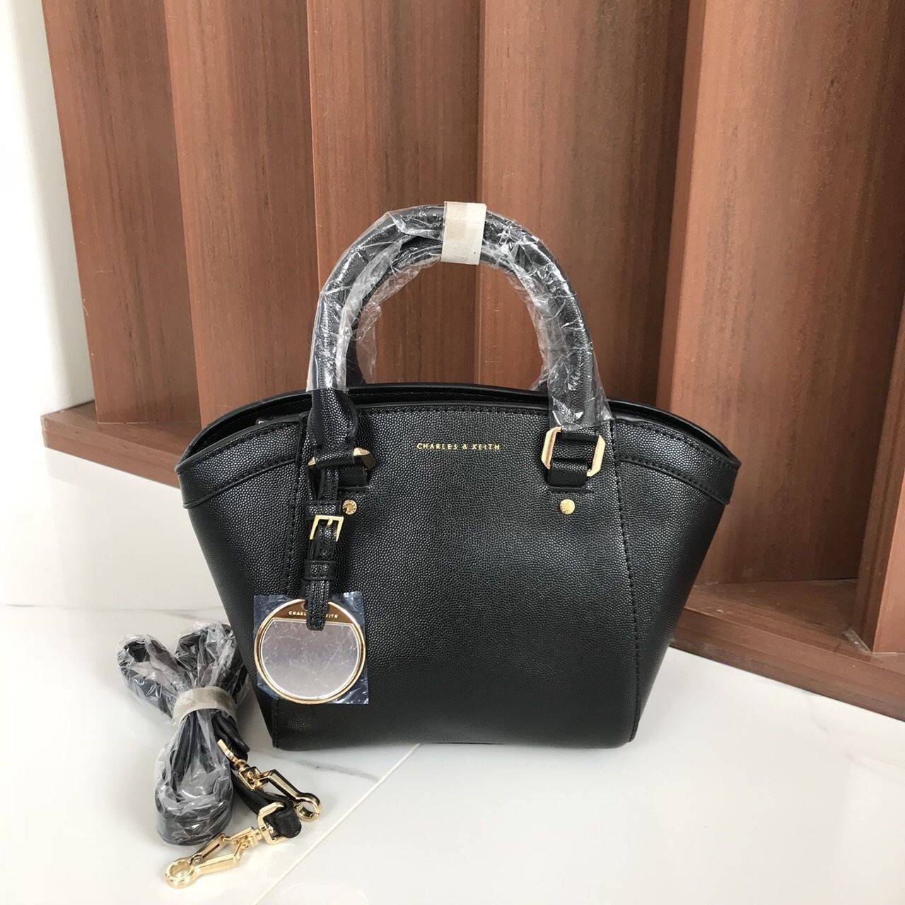 CHARLES & KEITH CITY BAG กระเป๋าถือหรือสะพาย ตั้งอยู่ทรงสวย มีโลหะรองฐาน เปิดปิดด้วยซิปเดียว ภายในมี 2 ช่องเล็กด้านหน้าประดับด้วยกระจกทรงกลม ใช้งานได้จริง ปั้มโลโก้แบรนด์ มาพร้อมสายสะพายยาว ปรับระดับและถอดสายได้ หูพับลงได้ น้ำหนักเบา ต้องมีไว้ครอบครองสักใ
