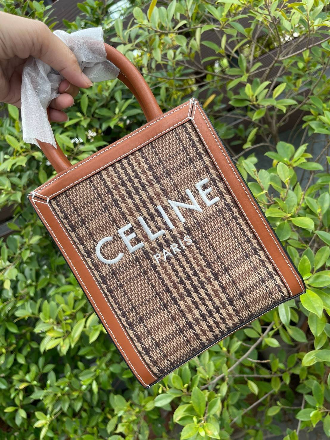 CELINE SMALL VERTICAL CABAS IN TEXTILE วัสดุหลักที่ใช้เป็นผ้าแคนวาสและขอบทำจากหนัง เป็นกระเป๋าถือที่มีสไตล์มินิมอล และดูเรียบง่าย แต่หรูหรา มีสายสะพายcrossbody พร้อมด้วยงานปักโลโก้ CELINE / PARIS สกรีนอยู่ตรงกลาง ถือเป็นกระเป๋า Tote ที่ทำจากแคนวาสที่น่าสน