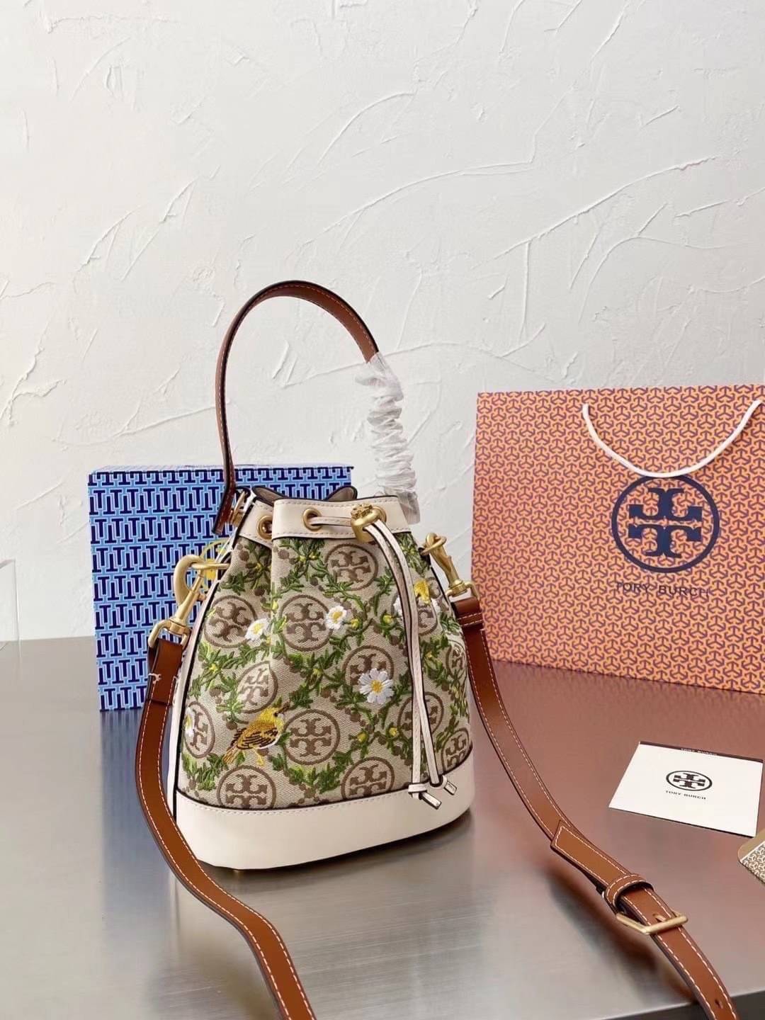 TORY BURCH T MONOGRAM JACQUARD EMBROIDERED BUCKET BAG ครั้งแรกกับโมโนแกรม ที่ได้รับแรงบันดาลใจมาจากโลโก้สุดคลาสสิก กลับมาอีกครั้งในรูปแบบของ ลวดลาย T Monogram ที่ผสมผสานความร่วมสมัยเข้ากับความเป็นเอกลักษณ์ของแบรนด์เข้าไว้ด้วยกัน โดยเป็นการนำเอาลวดลาย T Mo