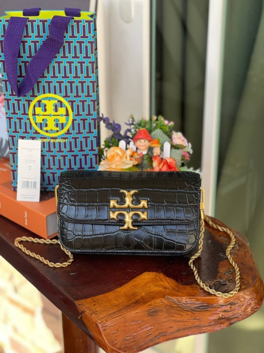 Tory Burch Eleanor Crocodile-Embossed Phone Crossbody Bag จุดเด่นของรุ่นนี้คือดีไซน์ออกมาในสไตล์คลาสสิกที่มาพร้อมกับฮาร์ดแวร์ที่ทำจากวัสดุทองเหลืองและสายสะพายโซ่เกลียวสีทอง ซึ่งการออกแบบได้รับแรงบันดาลใจมาจากเครื่องประดับ รูปทรงกะทัดรัดจึงสามารถสะพายใช้งา