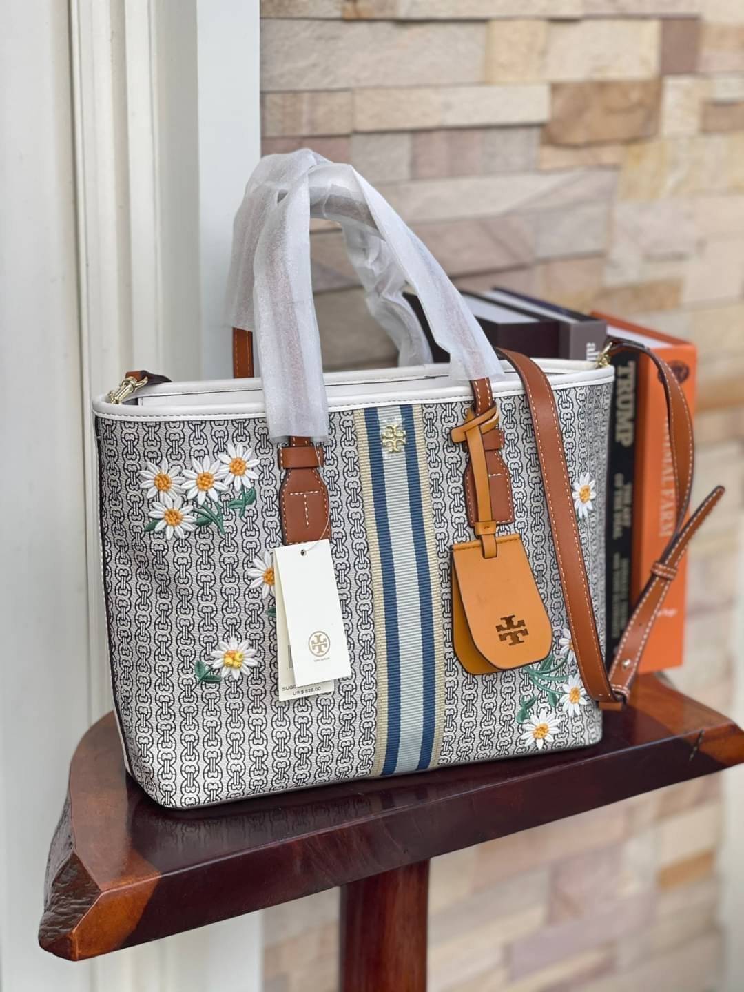 Tory burch Gemini Canvas Applique Small Tote Bag กระเป๋าสุดปังจากทอรี่ เบริช์(Tory Burch) อย่างเจมิไนลิงค์ ในทรง tote bag มีเอกลักษณ์โดดเด่นที่ลายทางตรงกลาง มีการพิมพ์แพทเทิรน์โซ่แบบเรียบหรู เพิ่มความน่ารักจากดอกเดรซี่ที่ถูกจัดวางให้ดูมีสีสัน มีสายสะพายให