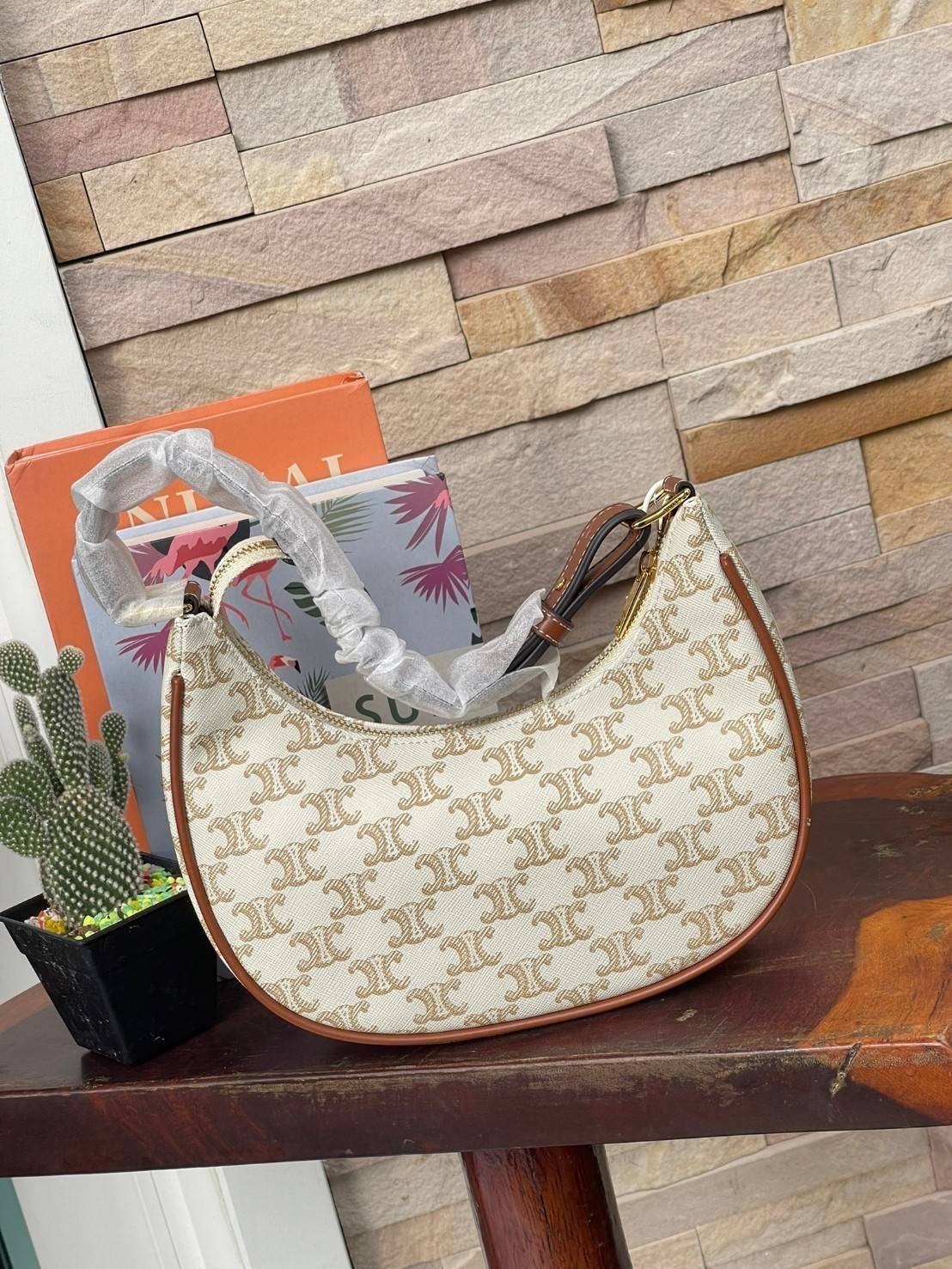 CELINE Vintage Classic Ava bag 1 ใน คอลเลคชั่น “Triomphe Canvas” มาพร้อมสายสะพายไหล่ที่ปรับความยาวได้ และเนื่องจากช่วงล่างของกระเป๋ามีขนาดใหญ่กว่าช่วงบน จึงทำให้ไม่เสียทรงเมื่อเราใส่สิ่งของอย่างกระเป๋าสตางค์หรือโทรศัพท์มือถือ หากดูภาพรวมแล้ว รุ่นนี้ออกแนว