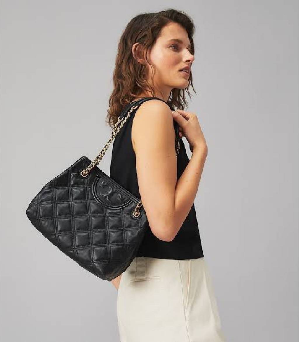 Tory Burch Fleming Soft Small Tote Bag เป็นกระเป๋าสะพายไหล่น่ารัก ๆ สักใบที่มีดีไซน์โดดเด่น สะดุดตา ใน Collection เรียกได้ว่าขายดีอันดับต้น ๆ ของแบรนด์ ใช้ได้ในลุคช์ทางการและกึ่งทางการ ดีเทลการตัดเย็บพิมพ์ลายนูนคู่กับแพทเทิร์นสี่เหลี่ยมทรงเพชร ที่ช่วยเพิ่