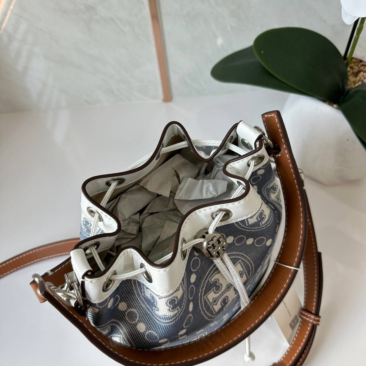 TORY BURCH T Monogram Denim Bucket Bag MEDIUM คอลเลคชั่นใหม่ รูปแบบคลาสสิค พกพาความหรูหราไปได้ทุกที่ด้วยกระเป๋าทรง Bucket ขนาดกลางและปิดด้วยเชือกรูดพร้อมโลโก้แวววาว วัสดุผ้าเดนิมแจ็คการ์ด ตัดขอบหนังแท้