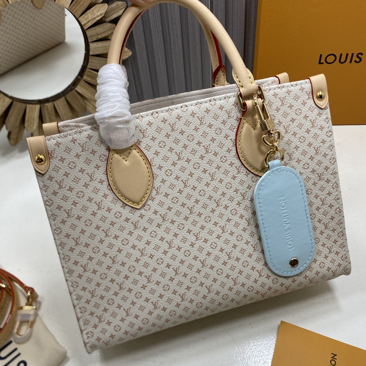 TOP ORI หนังแท้ | LV OnTheGo PM bag Azure Blue/Sand Beige กระเป๋าสะพายทรงโท้ท ในคอลเลกชัน LV Romance หนังแท้หรูหราประดับชาร์มแท็กกระเป๋าเดินทางมีชีวิตชีวา