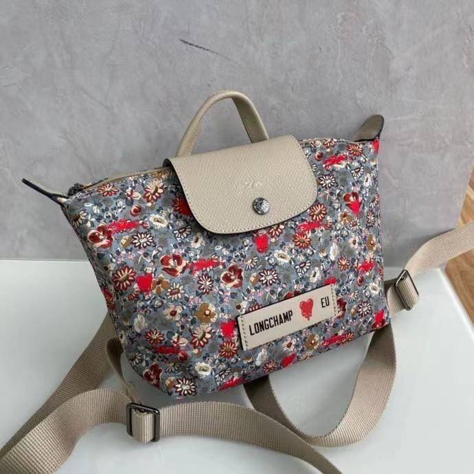 Longchamp X Eu Backpack กระเป๋าเป้สะพายหลังลายดอกๆไม้ วัสดุผ้าฝ้าย อะไหล่สีดำ กระเป๋าเป้แบบลำลองสำหรับสตรีซึ่งนำรูปทรงอันเป็นเอกลักษณ์ของ Le Pliage มาปรับใช้กับทุกสถานการณ์ อุปกรณ์เสริมที่ใช้งานได้จริงนี้มีสายรัดปรับระดับได้และที่จับช่วยให้ สะพายข้างหรือส