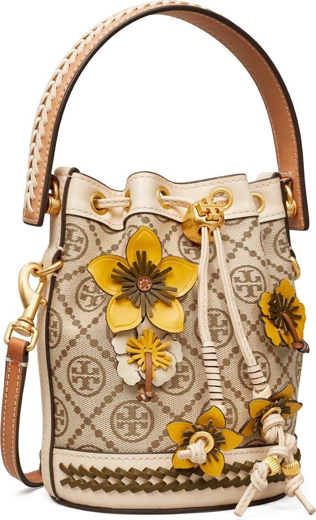 TORY BURCH MINI T MONOGRAM FLORAL BUCKET BAG คอลเลคชั่นใหม่ พร้อมเสิร์ฟความสวยให้ถึงบ้าน!! กระเป๋าบัคเก็ตทรงยอดนิยม ไซส์มินิ ดีไซน์ใหม่ล่าสุด สไตล์งานคราฟ มีลูกเล่นประดับดอกไม้กับตัวกระเป๋า และตัวรูดสาย วัสดุผ้า jacquard ตัดสลับหนังแท้ หูจับและขอบกระเป๋าต