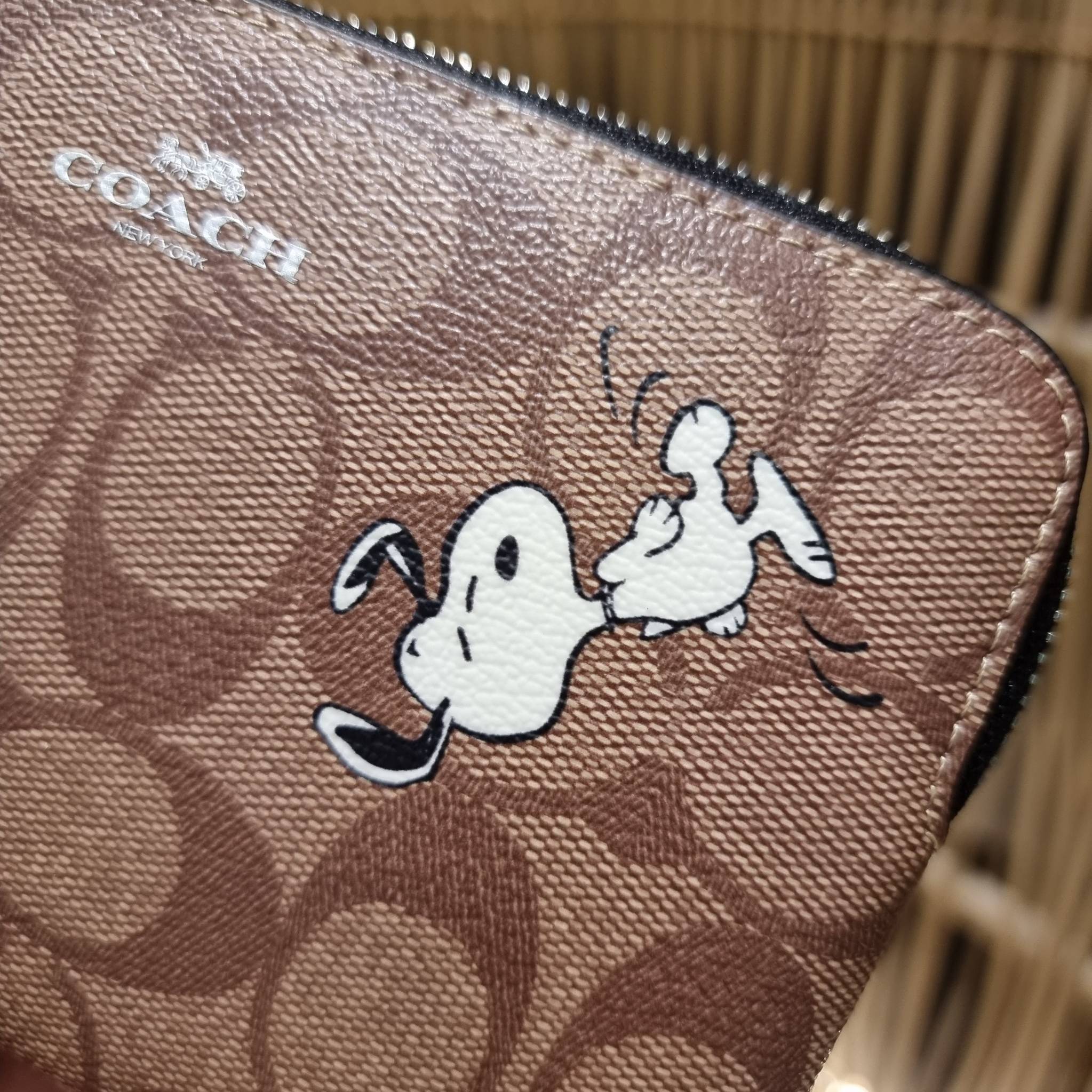 COACH C4589 COACH x PEANUTS CORNER ZIP WRISTLET IN SIGNATURE CANVAS WITH SNOOPY PRINT เหล่าผองเพื่อนและสนูปพีมาแล้วจ้า คอลเลคชั่นสุดน่ารักที่ฮอตไม่มีตก กระเป๋าคล้องมือ ขนาดเหมาะพกพากำลังเหมาะ วัสดุหนังแคนวาสเคลือบลาย ภายในเป็นช่องโล่ง ใส่ธนบัตร หรือใส่บัต