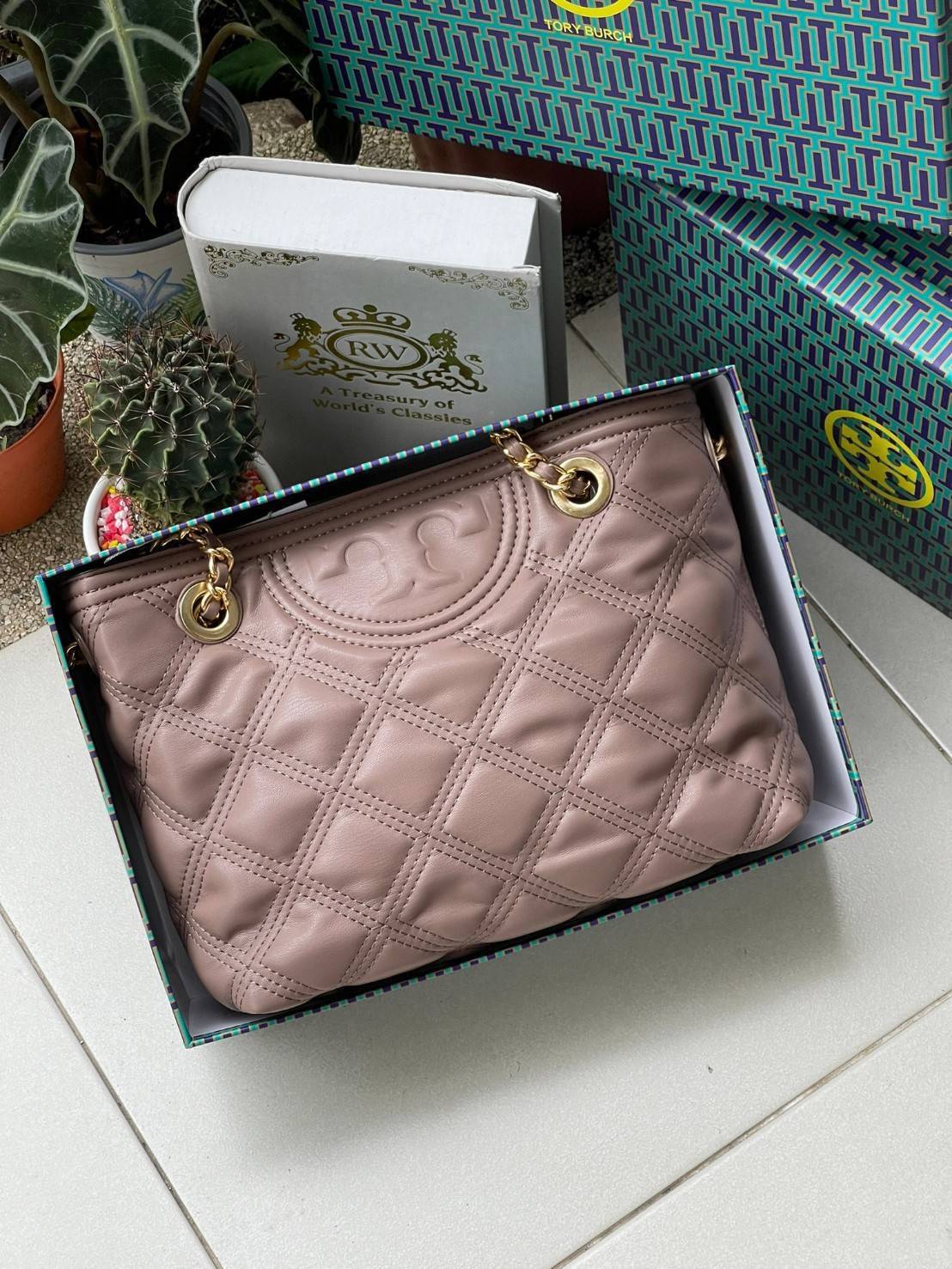 Tory Burch Fleming Soft Small Tote Bag เป็นกระเป๋าสะพายไหล่น่ารัก ๆ สักใบที่มีดีไซน์โดดเด่น สะดุดตา ใน Collection เรียกได้ว่าขายดีอันดับต้น ๆ ของแบรนด์ ใช้ได้ในลุคช์ทางการและกึ่งทางการ ดีเทลการตัดเย็บพิมพ์ลายนูนคู่กับแพทเทิร์นสี่เหลี่ยมทรงเพชร ที่ช่วยเพิ่