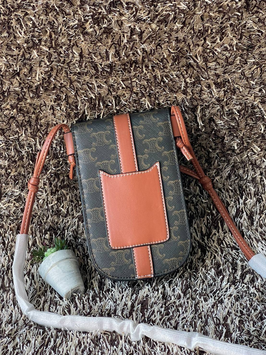 Celine Phone Pouch in Triomphe Canvas กระเป๋าใส่โทรศัพท์รุ่นนี้ มีดีไซน์ดูเรียบง่าย แต่ดูหรูหราด้วยลวดลาย Triompe ที่แสดงถึงความเป็นเอกลักษณ์ของ celine ช่องหลักที่มีความกว้าง สามารถใส่โทรศัพท์มือถือ ธนบัตร บัตรต่าง ๆ และของจุกจิกชิ้นเล็ก ๆ ได้แบบจุใจ หรือ