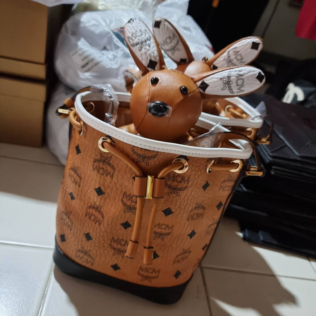 M.C.M ZOO RABBIT DRAWSTRING BAG IN VISETOS LEATHER MIX คอลเลคชั่นซูมาใหม่ ฮิตหนักมากที่เกาหลีและญี่ปุ่น ไอเท็มสุดคิ้วท์ น้องกระะต่ายโดดเด่น กระเป๋าสะพายทรง bucket ไซส์เล็กขนาดน่ารักน่าใช้ แฟชั่นสไตล์มากใบนี้ ดีไซน์น้องกระต่ายแอบในกระเป๋า และสามารถนำออกมาห