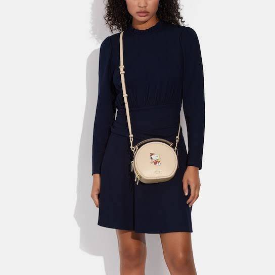 COACH X PEANUTS CANTEEN CROSSBODY WITH SNOOPY PRESENT MOTIF (CE845,CF290) กระเป๋าสะพายข้างทรงกลมไซส์มินิ มีหูจับ วัสหนังแท้ ด้านหน้าโดดเด่นด้วยรูปการ์ตูนSnoopy