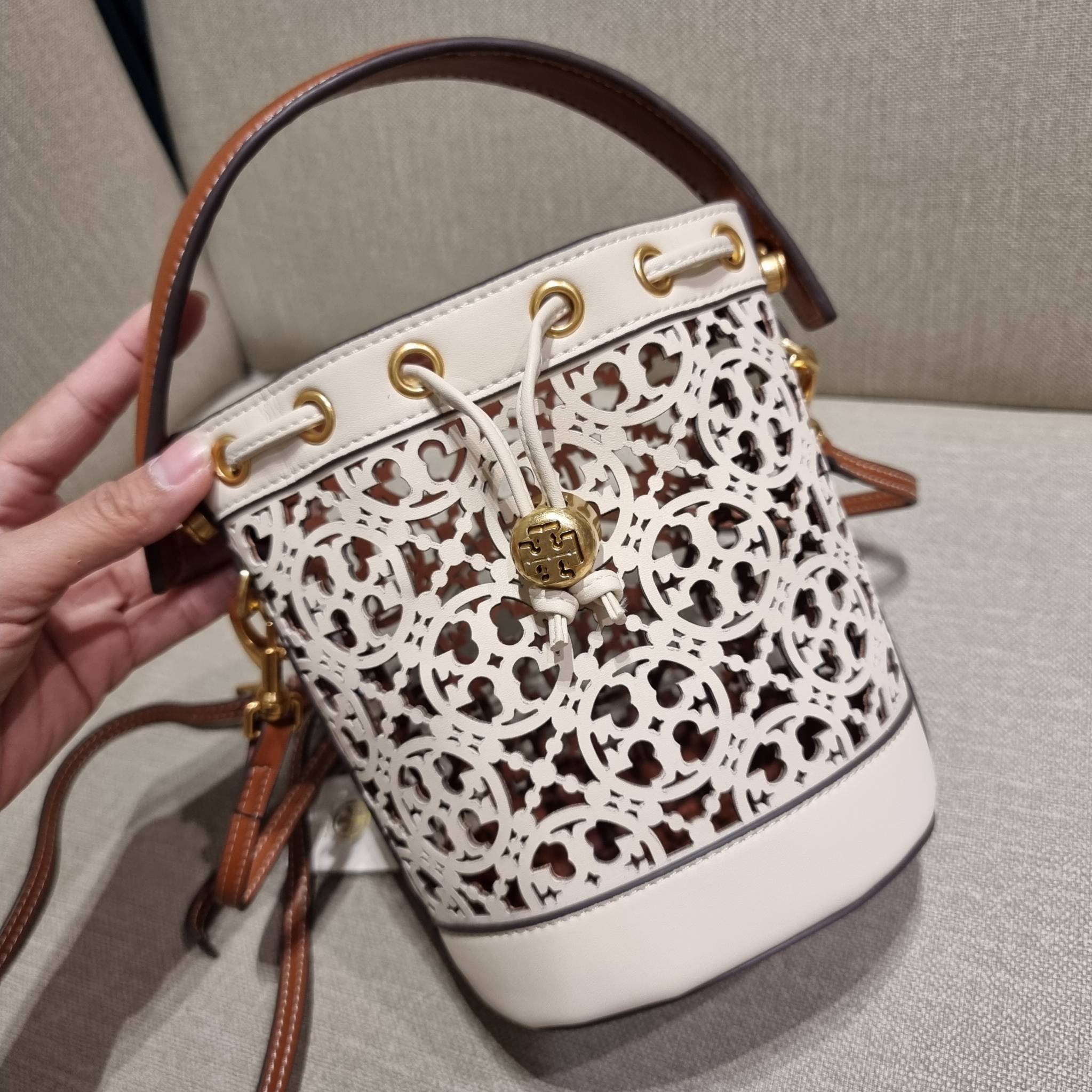 TORY BURCH T MONOGRAM LASER-CUT MINI BUCKET BAG ใจบางที่สุดกับคอลเลคชั่นนี้ กับกระเป๋าสะพายทรงบัคเก็ต ไซส์มินิ รุ่นชูโรงสุดฮิต ที่เพิ่มดีเทลความแพงด้วยการฉลุลวดลายโมโนแกรมรอบใบ ถักทอเป็นเส้นลายสานที่สวยงามมาก งานฝีมือจริงๆ วัสดุหนัง cowhide รูดเปิด-ปิดด้ว