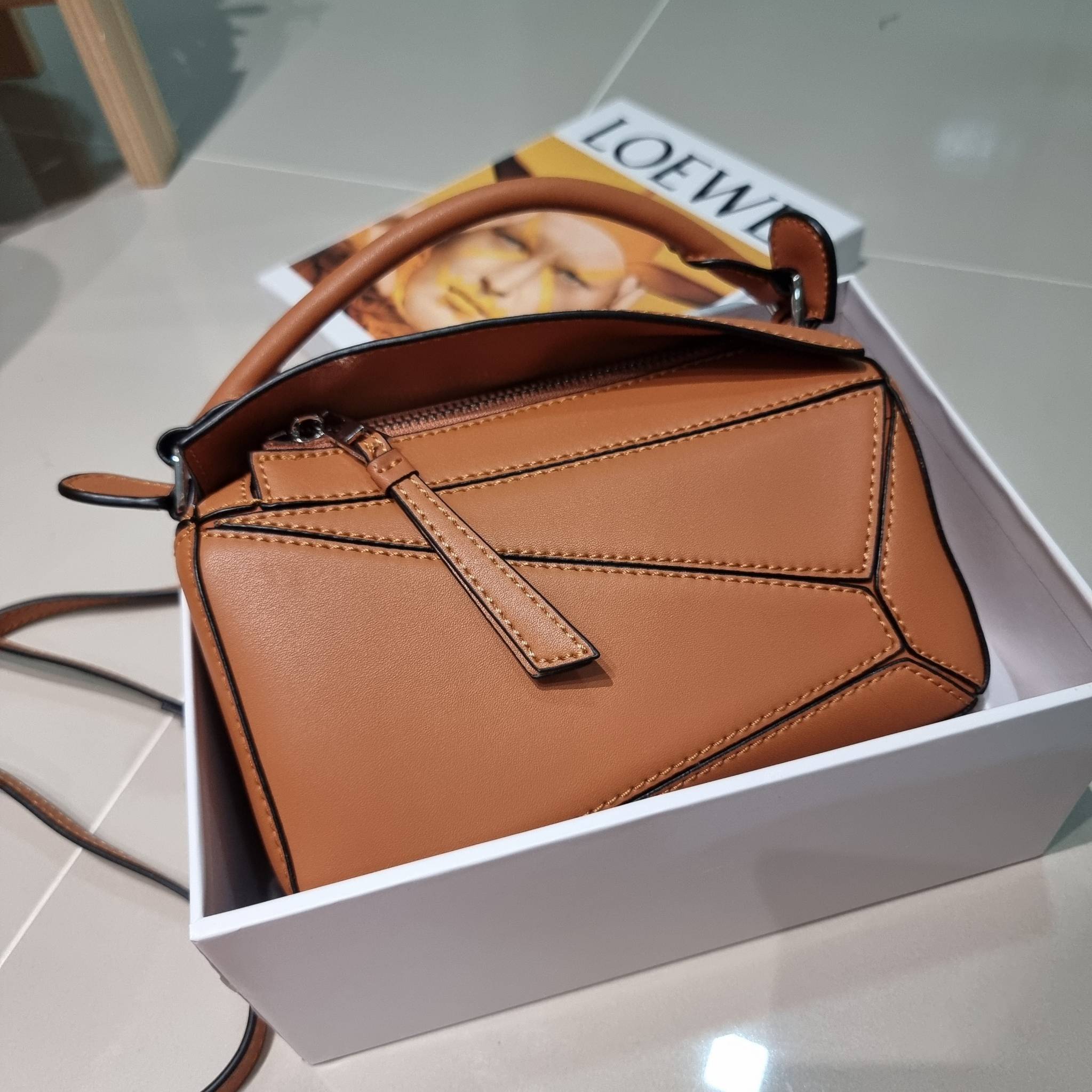 LOEWE MINI PUZZLE BAG IN CLASSIC สุดยอดแบรนด์ที่ดีไซน์เป็นเอกลักษณ์ โดดเด่น สวยหรู กับกระเป๋าสะพายข้างทรงกล่อง ไซส์มินิ สไตล์พัซเซิล ให้ฟีลลิ่งเหมือนตัวต่อคละสี ดูดีได้ทุกที่แค่มีใบนี้