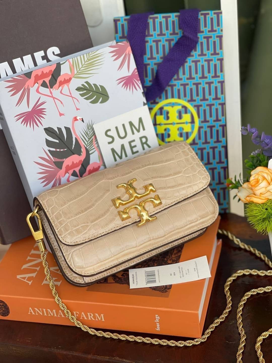 Tory Burch Eleanor Crocodile-Embossed Phone Crossbody Bag จุดเด่นของรุ่นนี้คือดีไซน์ออกมาในสไตล์คลาสสิกที่มาพร้อมกับฮาร์ดแวร์ที่ทำจากวัสดุทองเหลืองและสายสะพายโซ่เกลียวสีทอง ซึ่งการออกแบบได้รับแรงบันดาลใจมาจากเครื่องประดับ รูปทรงกะทัดรัดจึงสามารถสะพายใช้งา