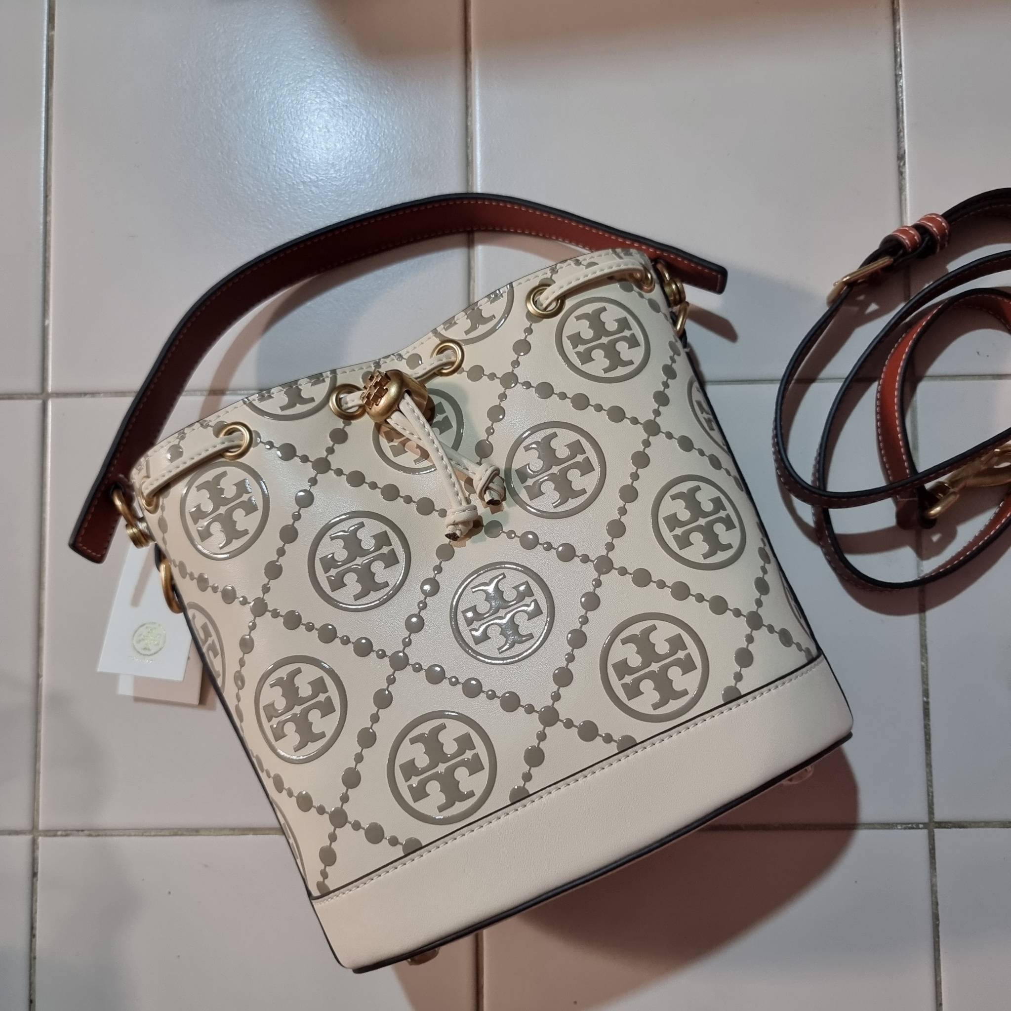 TORY BURCH T MONOGRAM EMBOSSED BUCKET BAG คอลเลคชั่นใหม่ กับกระเป๋าบัคเก็ตทรงยอดนิยม ดีไซน์ใหม่ล่าสุด สวยลูกคุณหนู หรูหรา!! ด้วยดีเทลผิวลายนูนลวดลายเอกลักษณ์ วัสดุหนังแท้ ปากกระเป๋ารูดเปิด-ปิดได้ มีหูจับในตัว สะดวกใช้ไปอีก และมีสายสะพายข้าง ปรับได้อีกด้วย
